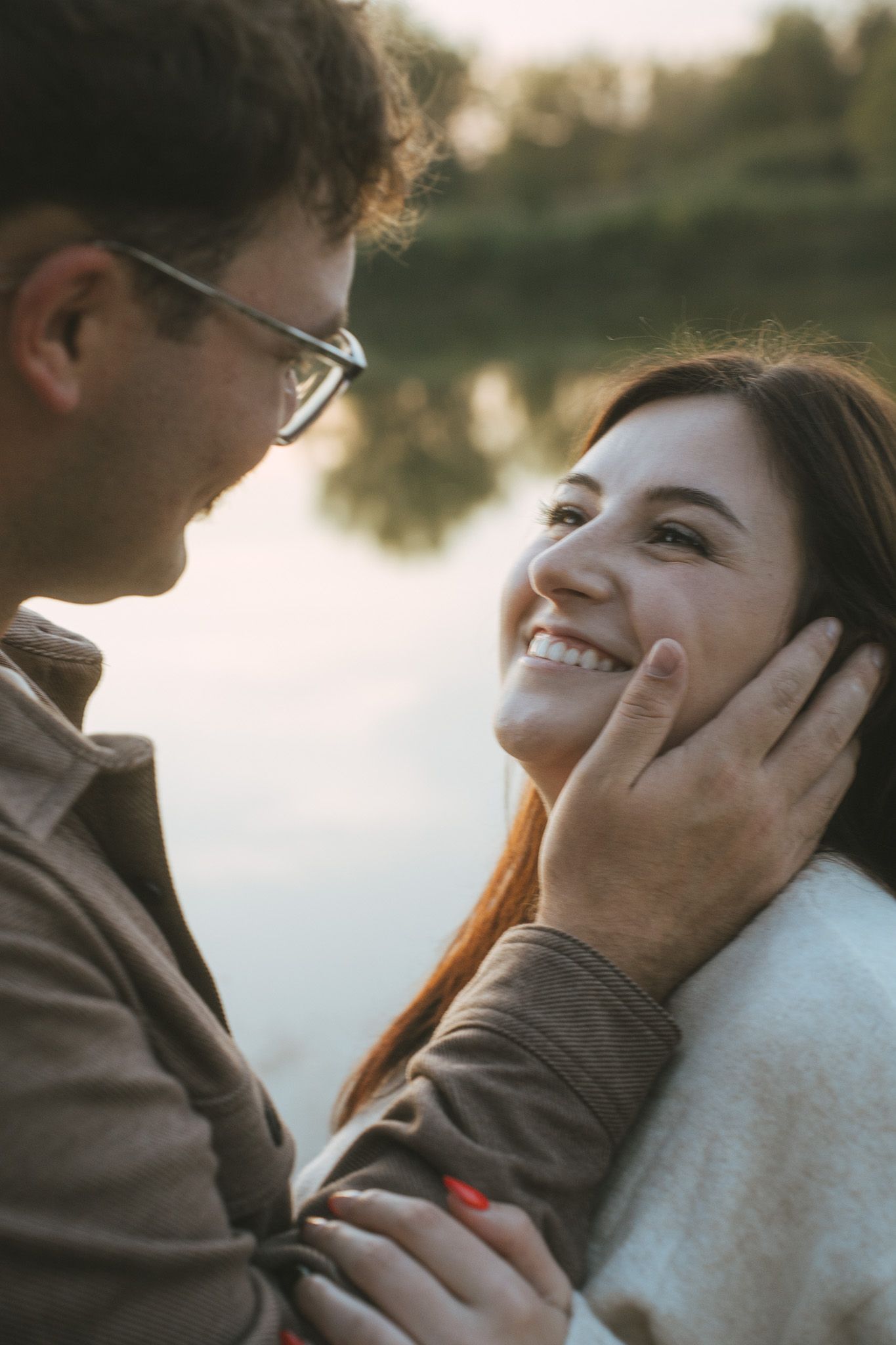 Tender moment between two people by a lake during golden hour.