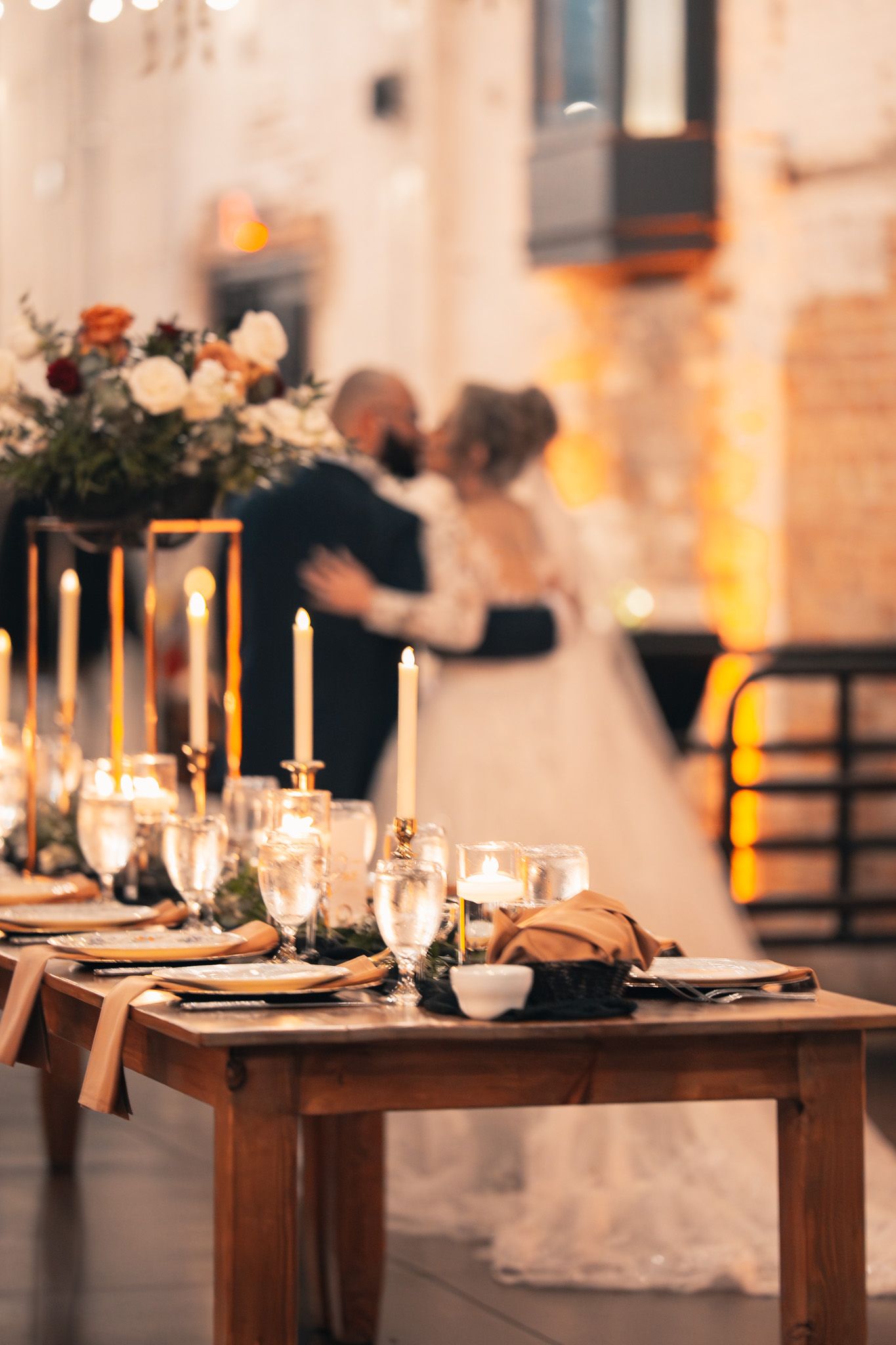 Elegant wedding reception table settings with glowing candles and rustic wooden tables create a romantic atmosphere.