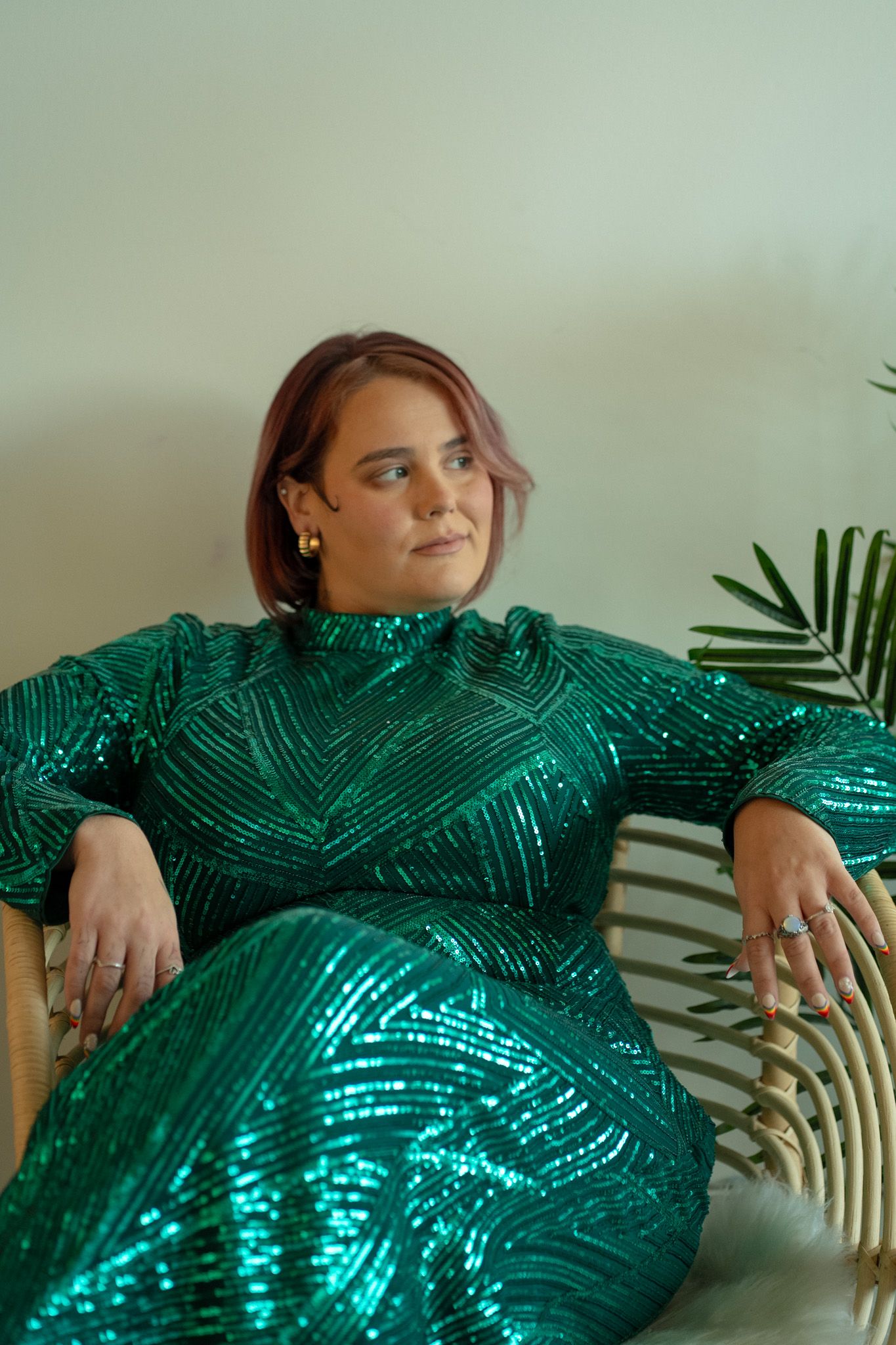 A sparkly emerald green sequin dress photographed against tropical leaves.