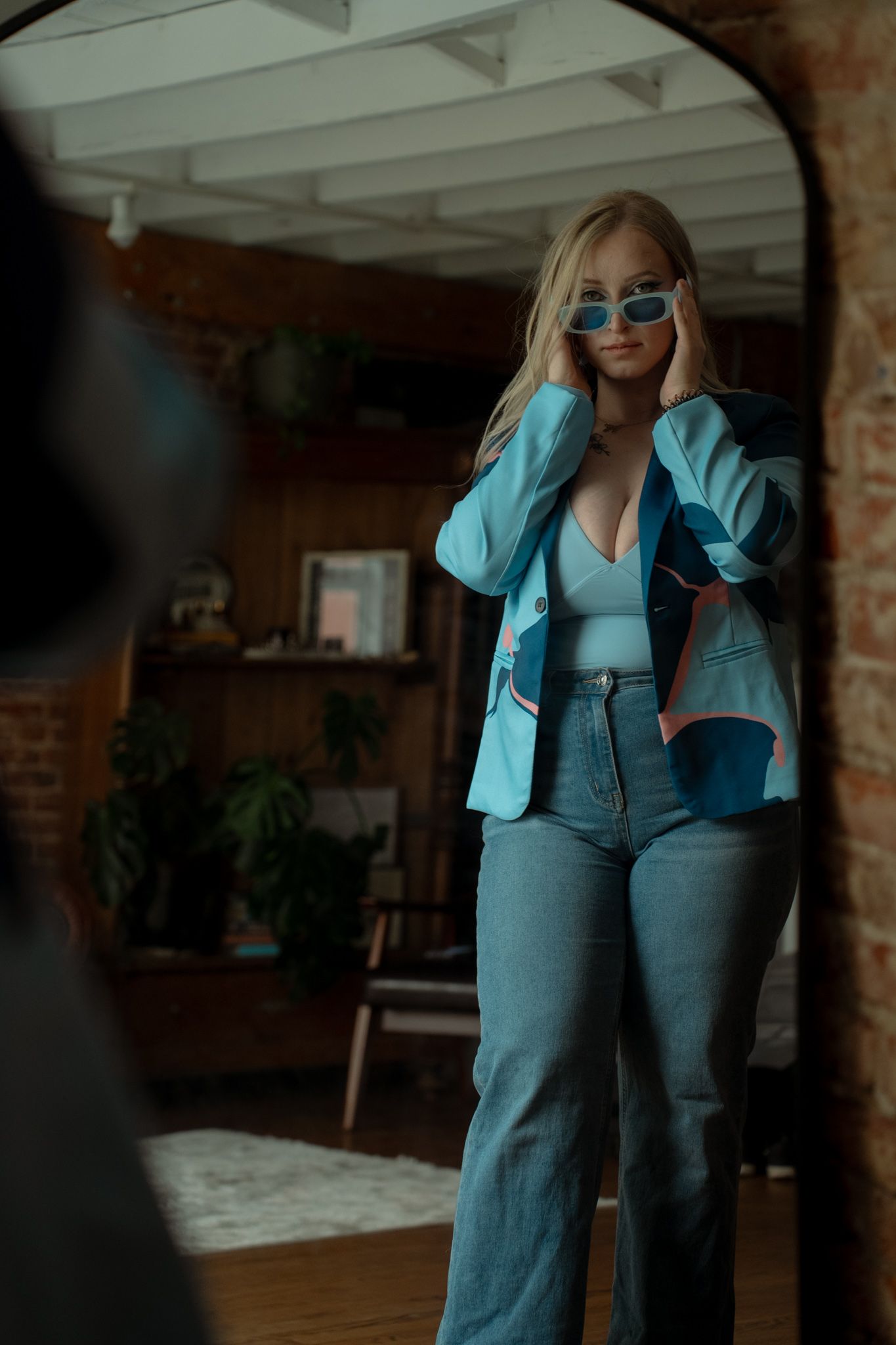 A person wearing a light blue blazer and dark pants poses in different positions against a dark interior background.