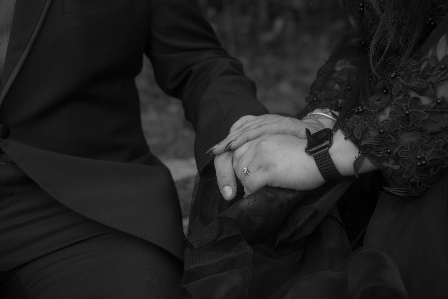 Close-up black and white shot of two hands clasped together showing emotional connection.