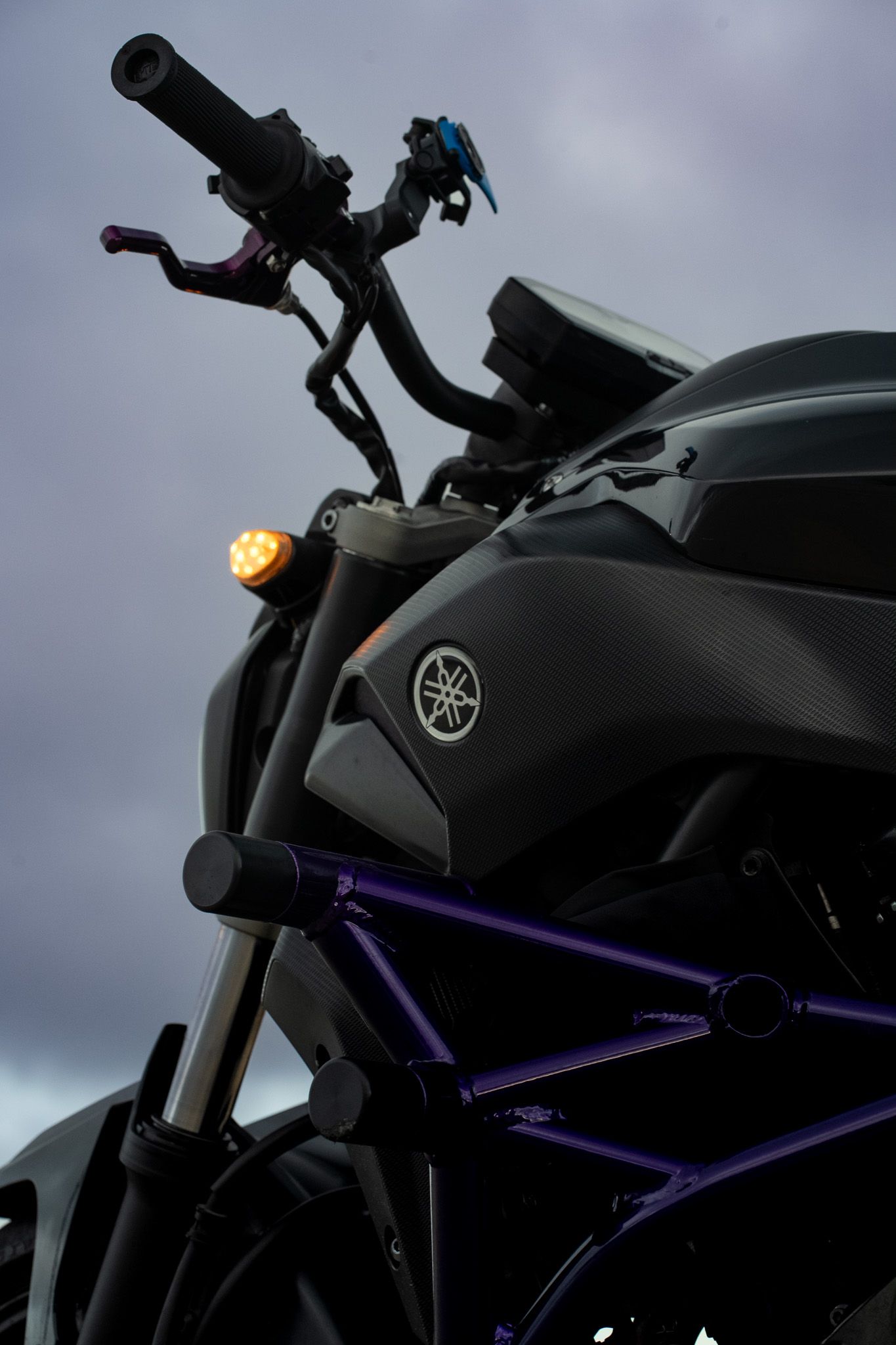 Close-up detail of a black Yamaha motorcycle's handlebar and frame with purple accents.