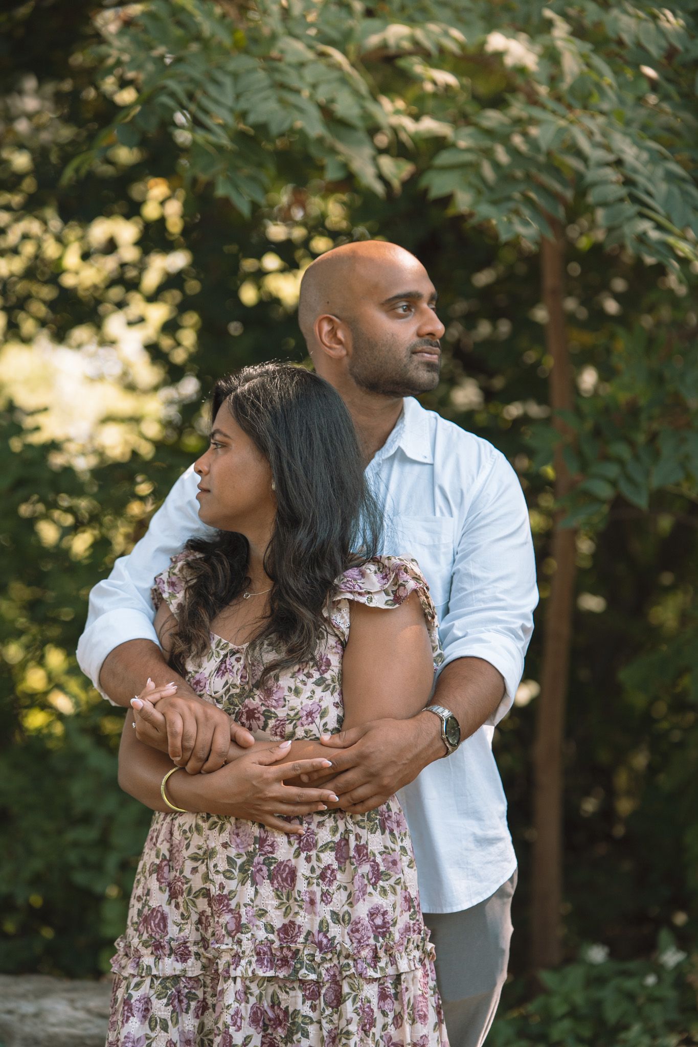 Couple embracing outdoors in front of fall foliage during sunset.