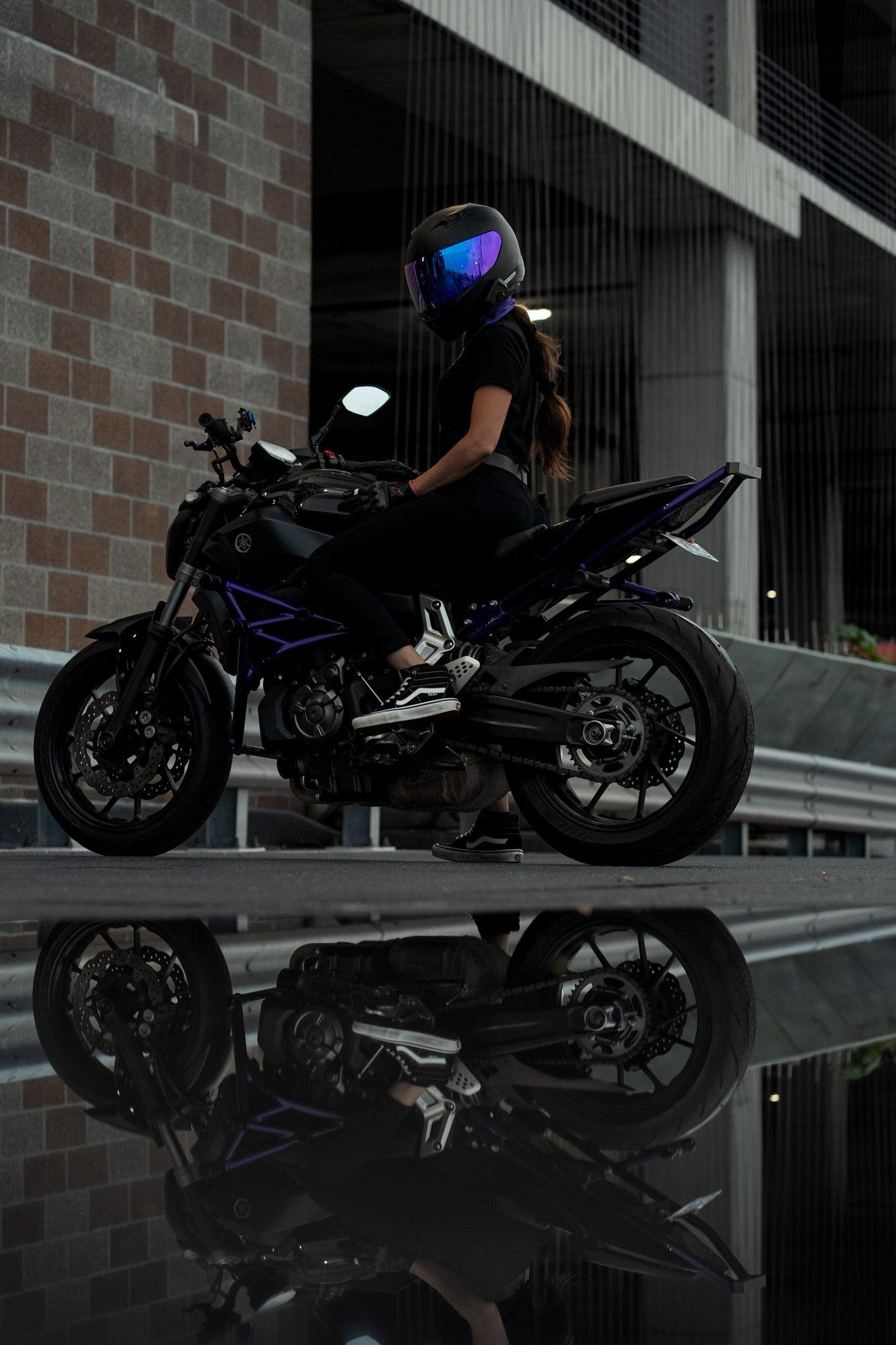 Sport bike with reflection on wet surface against brick wall background.