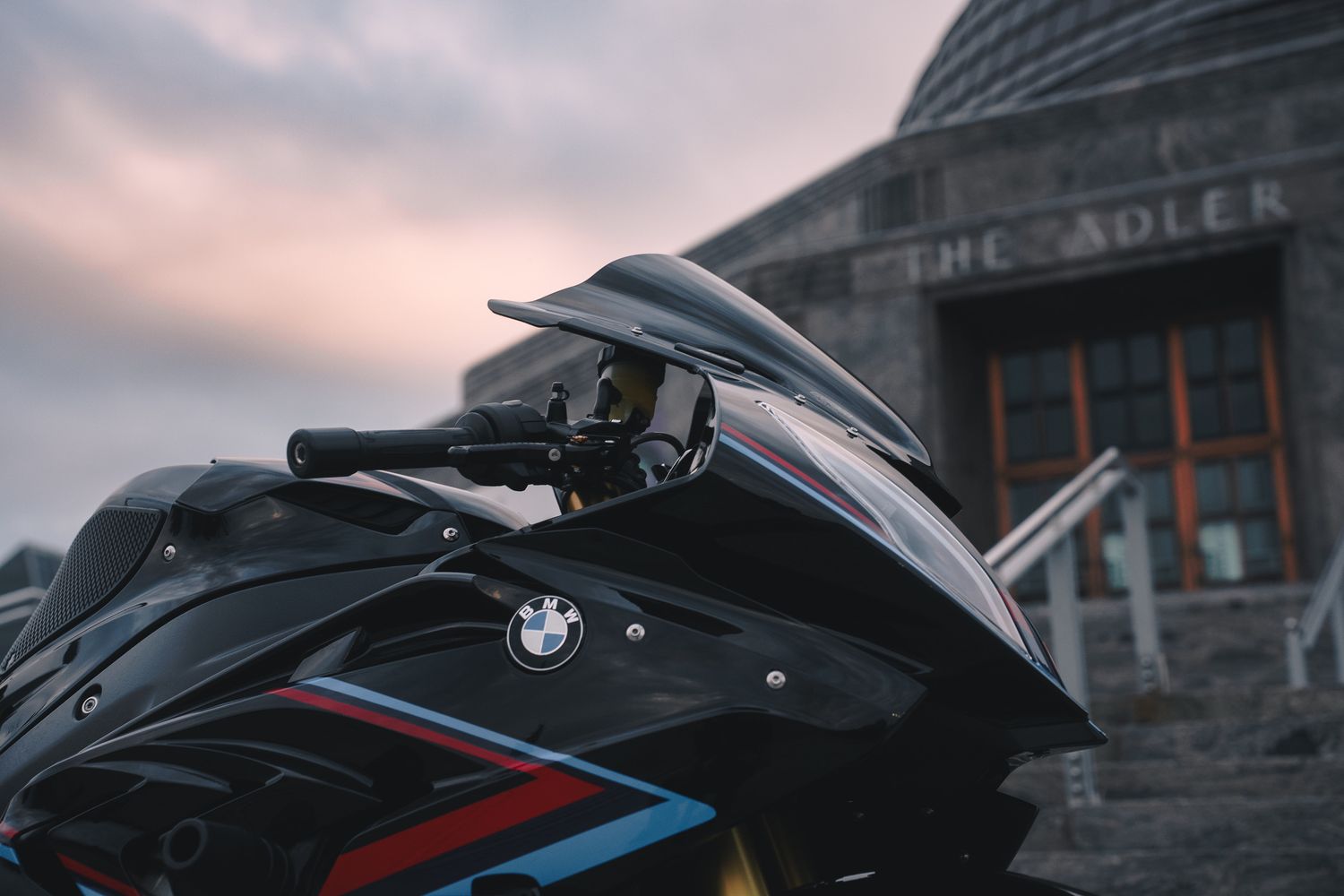 Close-up of a black BMW motorcycle with red and blue racing stripes at dusk.