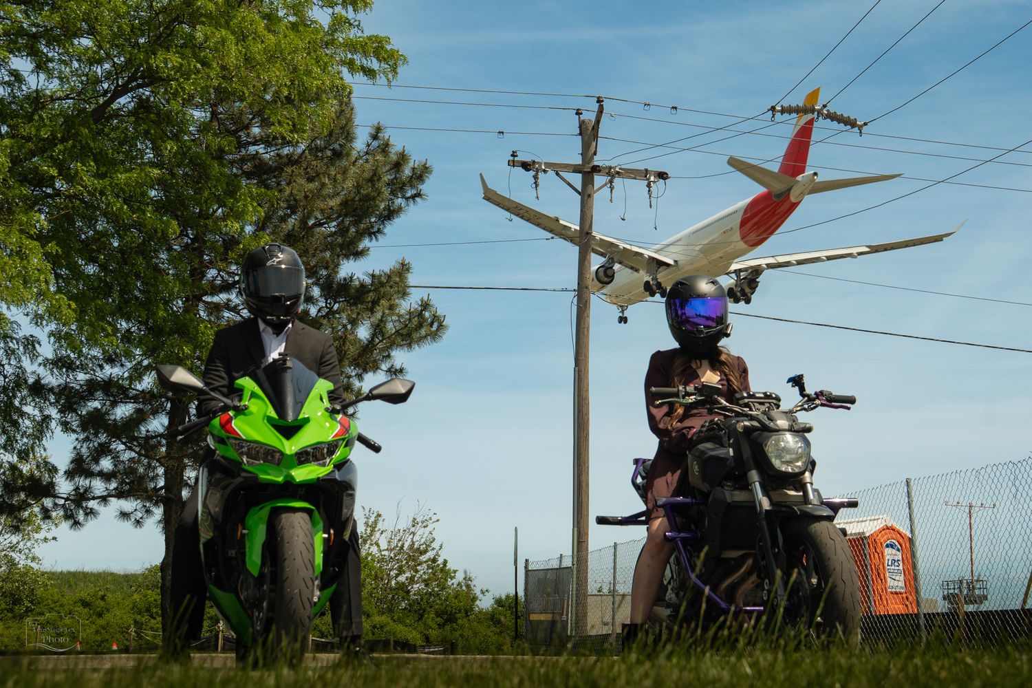 Motorcycles parked along rural road with power lines and trees.