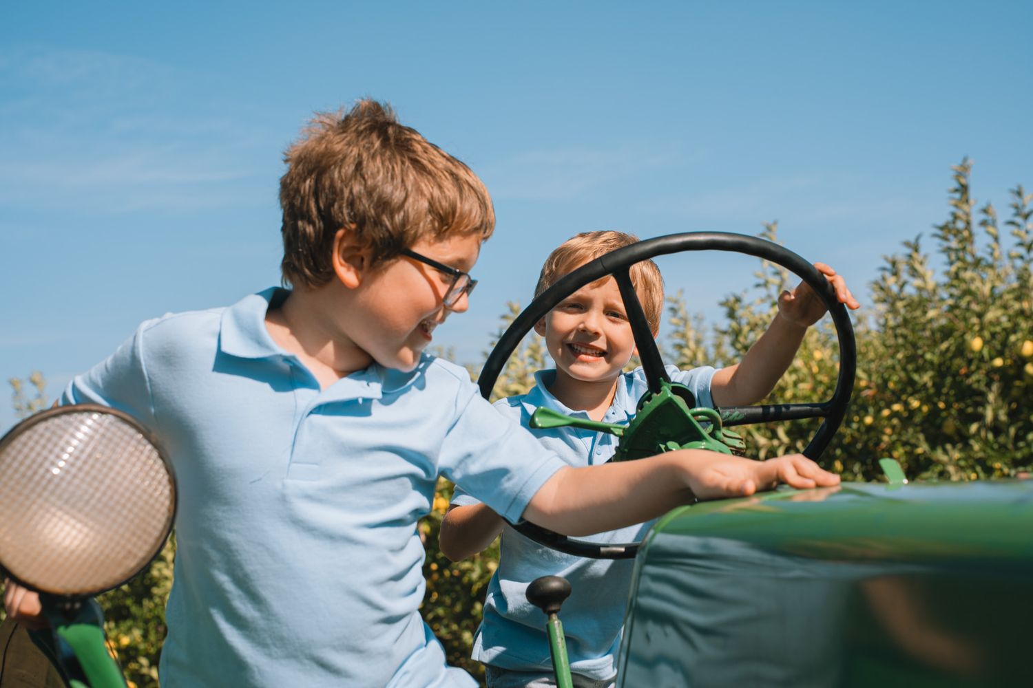 Children playing outdoors in light blue shirts on sunny day.