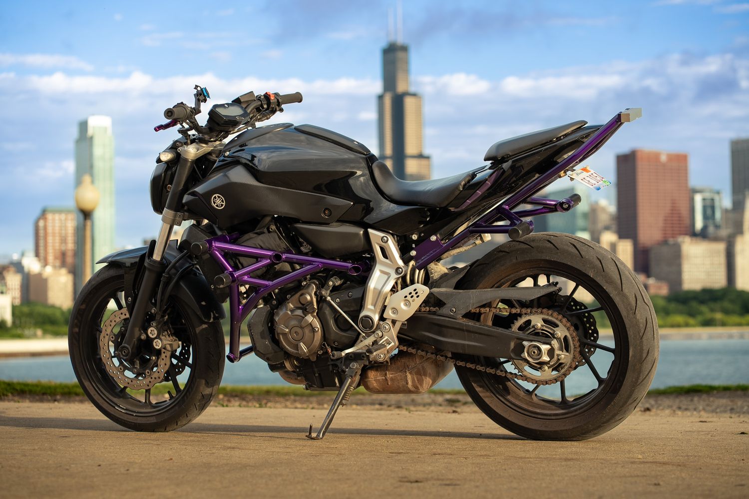 Sleek black motorcycle with purple frame highlights against Chicago skyline.