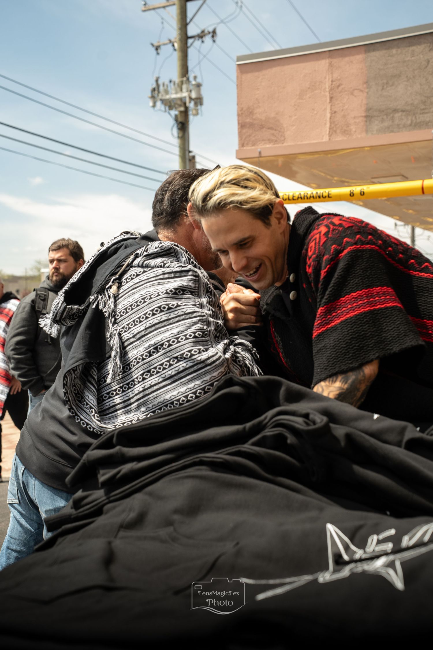 People huddled together examining black clothing with printed designs.