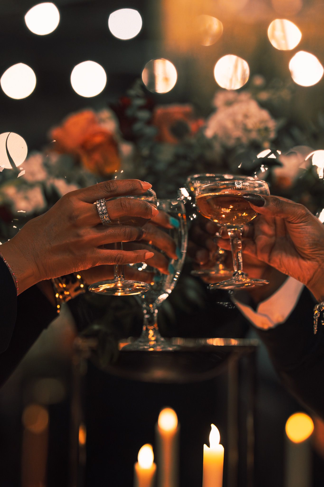 Wedding guests toasting with champagne glasses in candlelit ambiance.