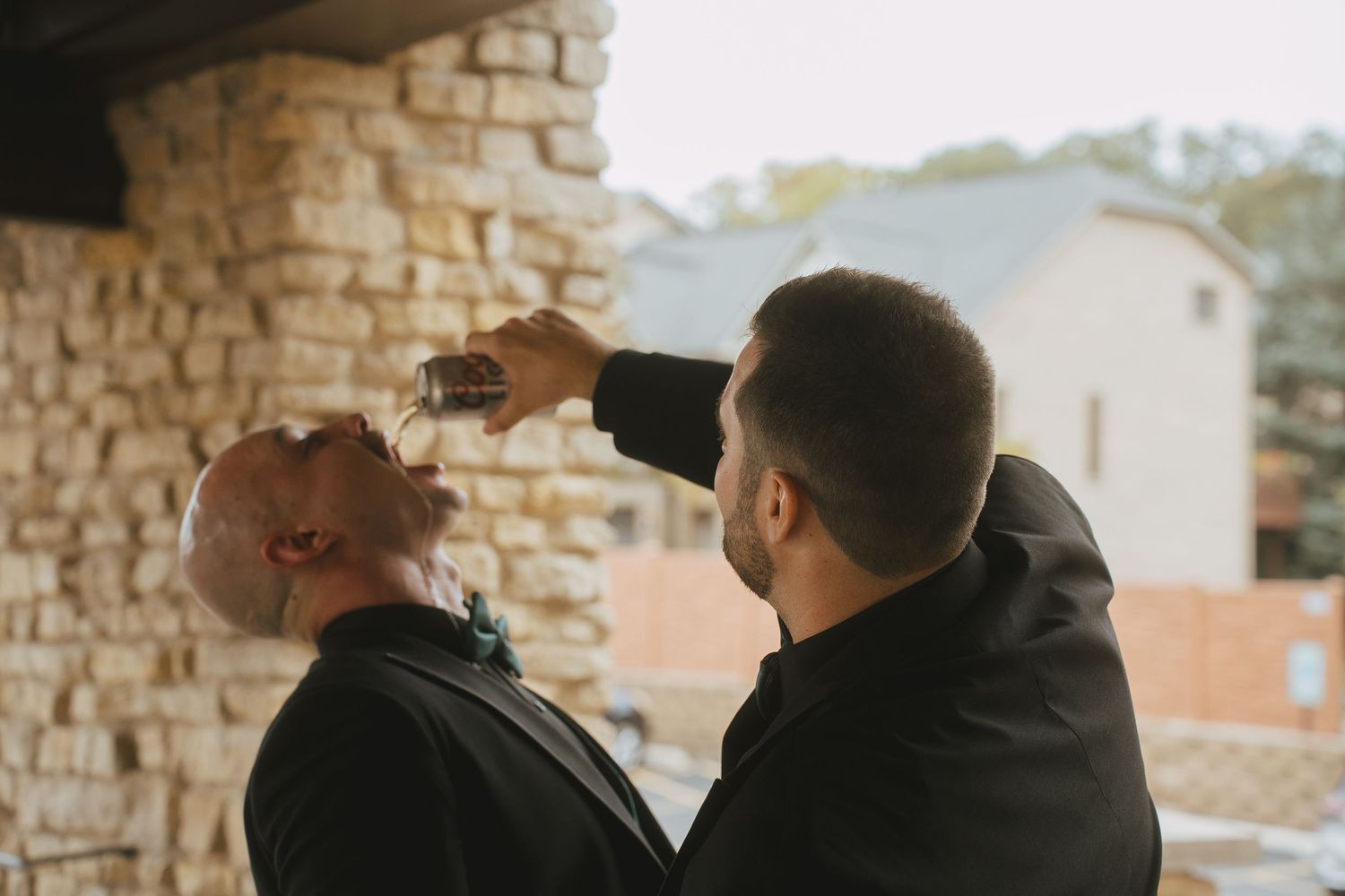 Two people sharing a playful moment against a stone wall backdrop.