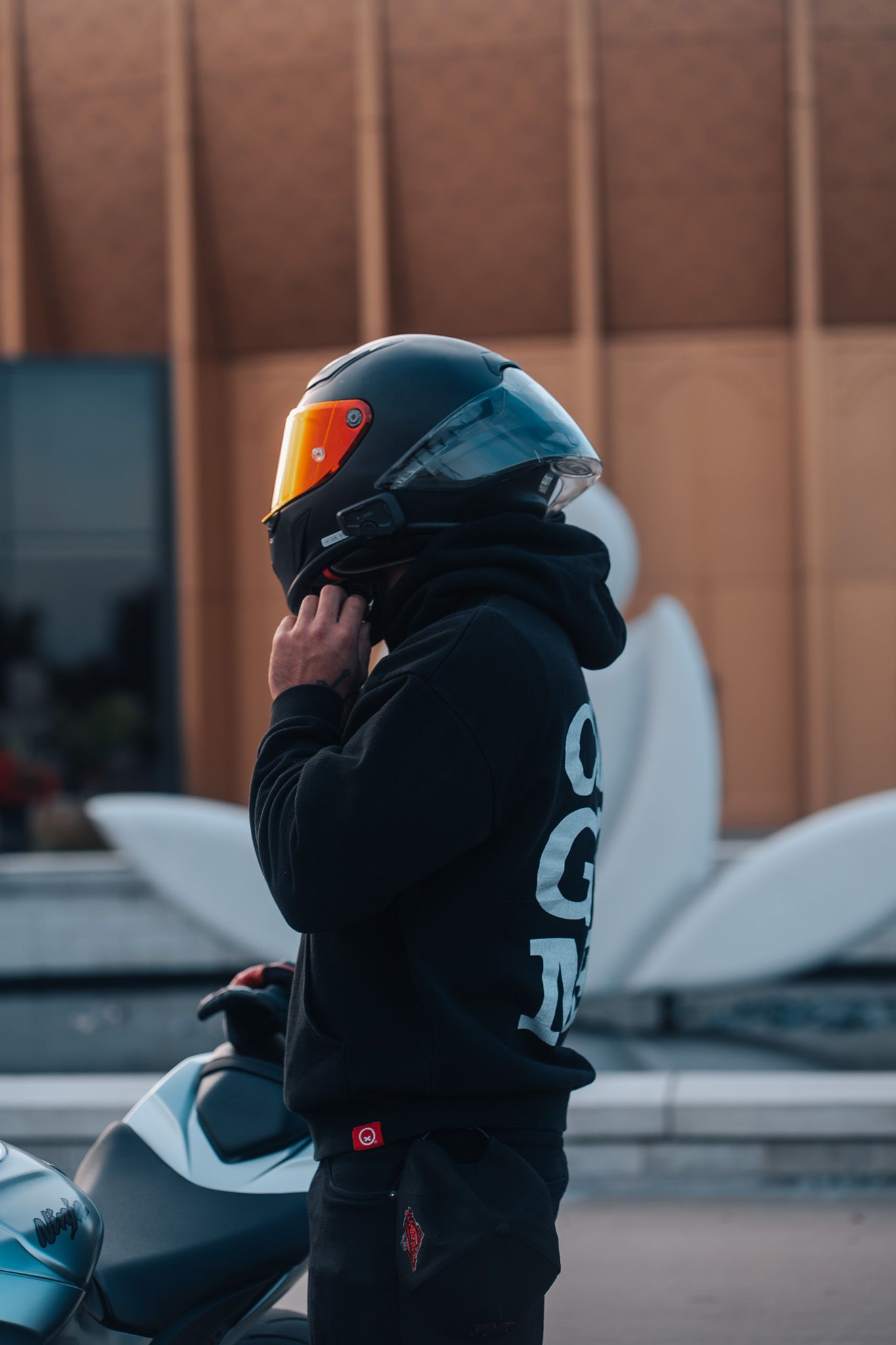 Motorcyclist wearing black helmet and protective gear at dusk.
