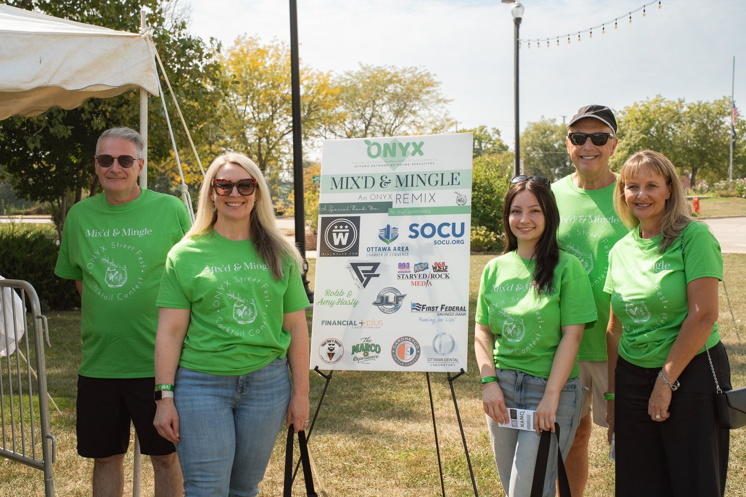 Group of volunteers in matching green t-shirts at an outdoor community event.