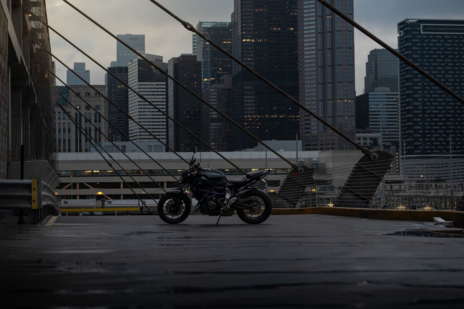 Dark motorcycles silhouetted against towering skyscrapers during overcast evening.