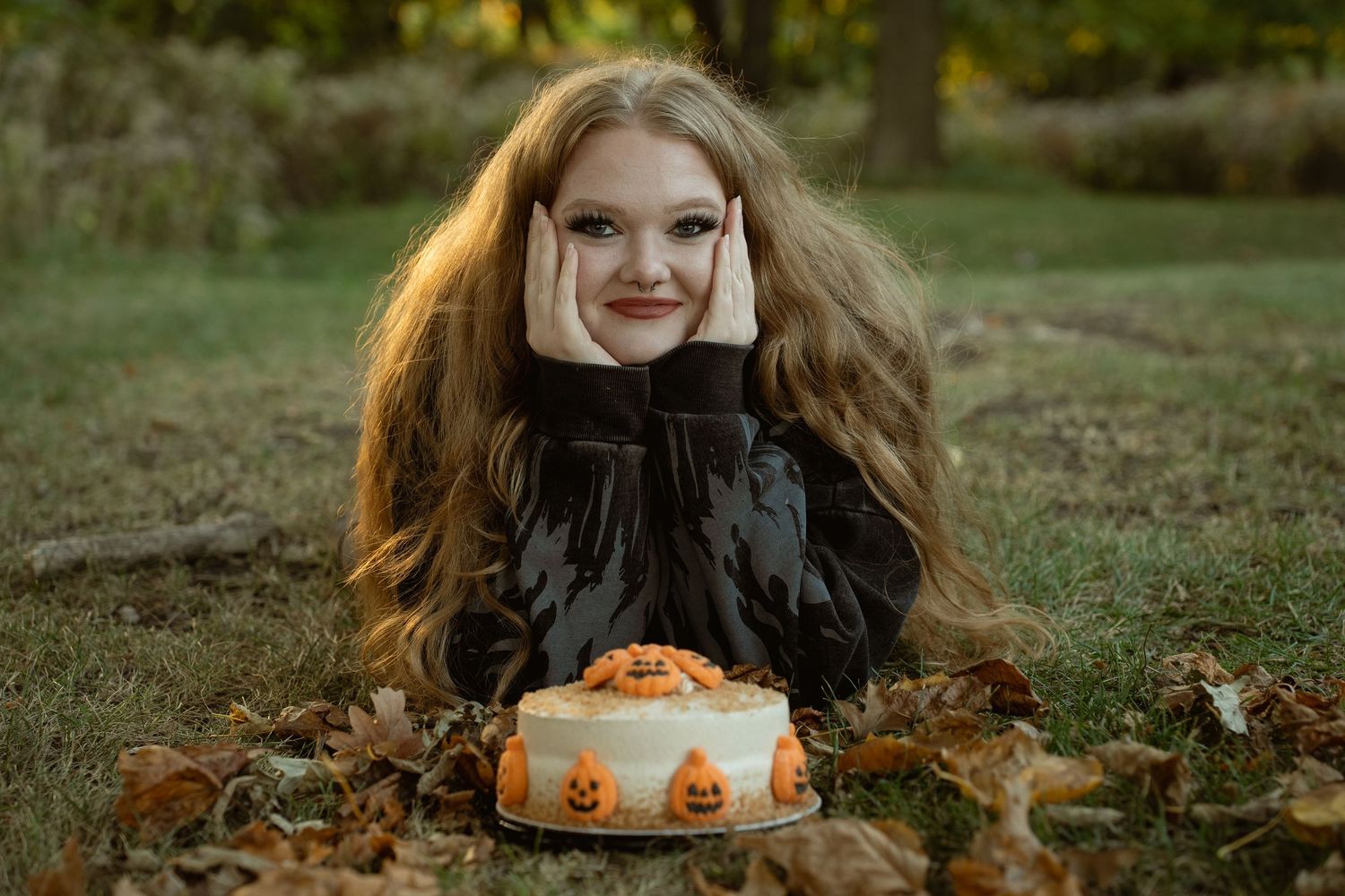 An autumn-themed portrait with a Halloween decorated cake surrounded by fallen leaves.