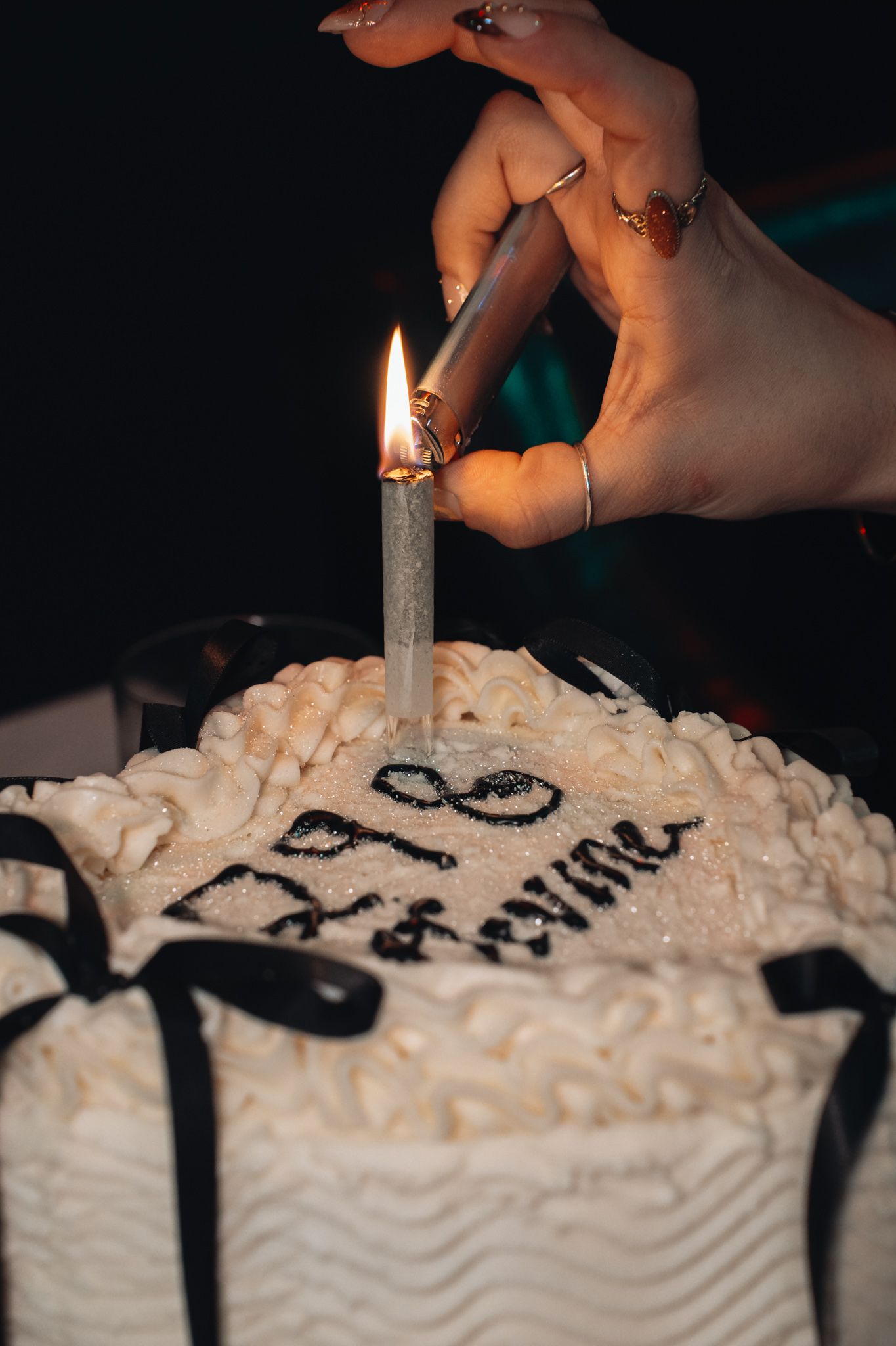 A sequence of photos showing a birthday candle being lit on a white frosted cake with black decorative details.