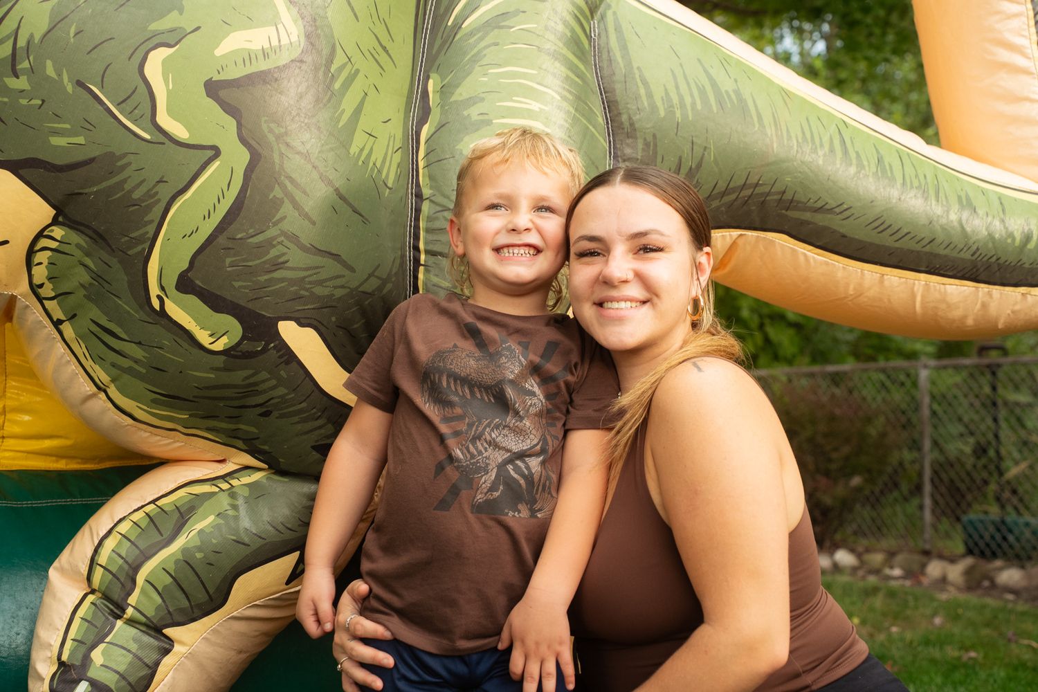 Fun outdoor moment with inflatable dinosaur prop in a backyard setting.