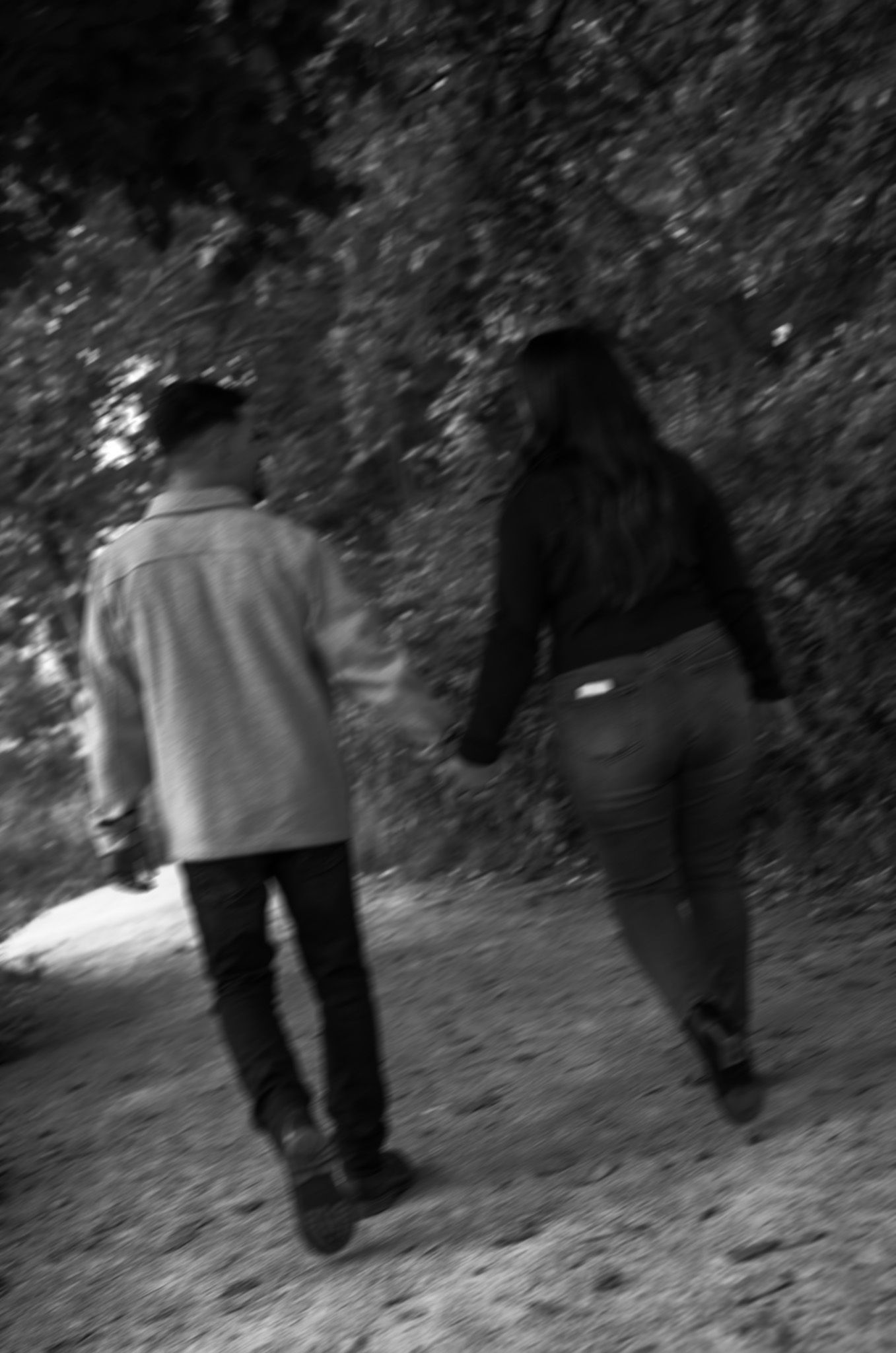 Black and white image of people walking through a wooded path.