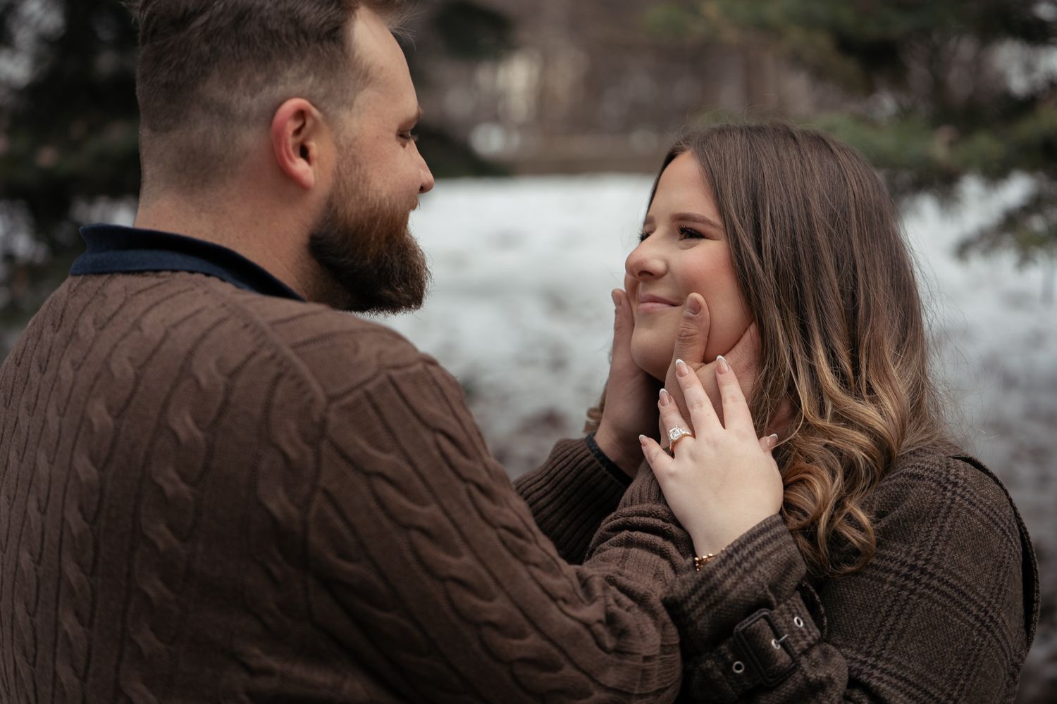 Romantic couple in brown sweaters share intimate moments in a winter outdoor setting.