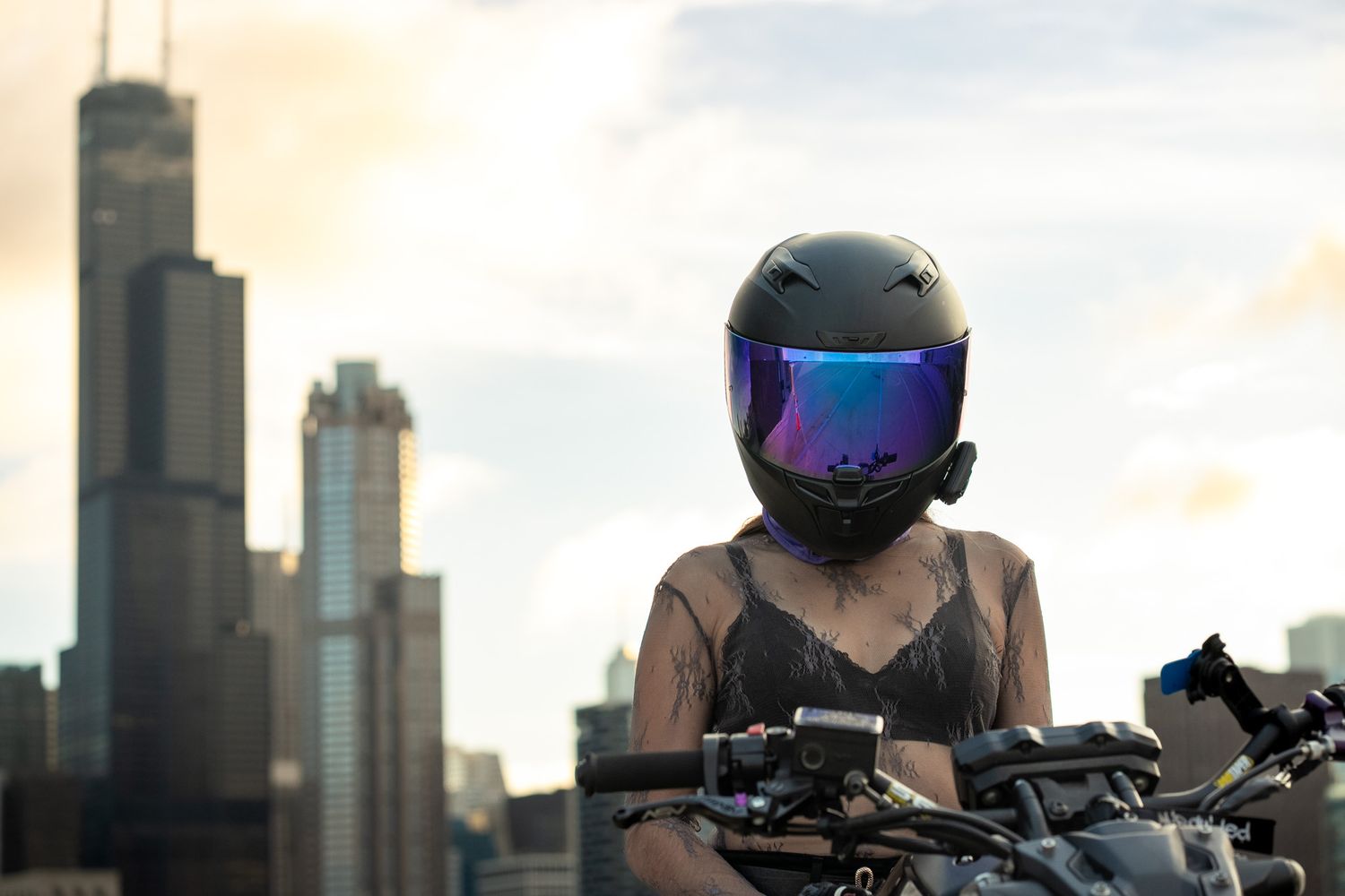 Rider in protective gear silhouetted against urban skyline during golden hour.