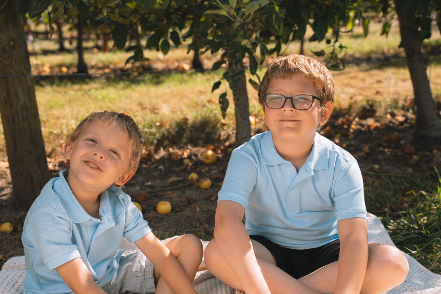 Group portrait of boys in matching blue shirts under sunny sky.