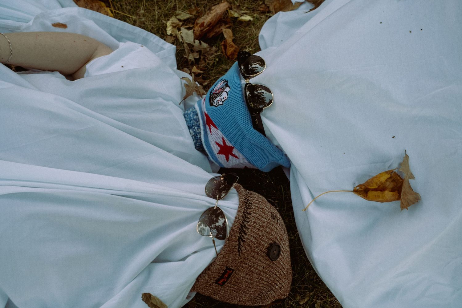 A white dress and blue converse shoes peek through on a picnic blanket.