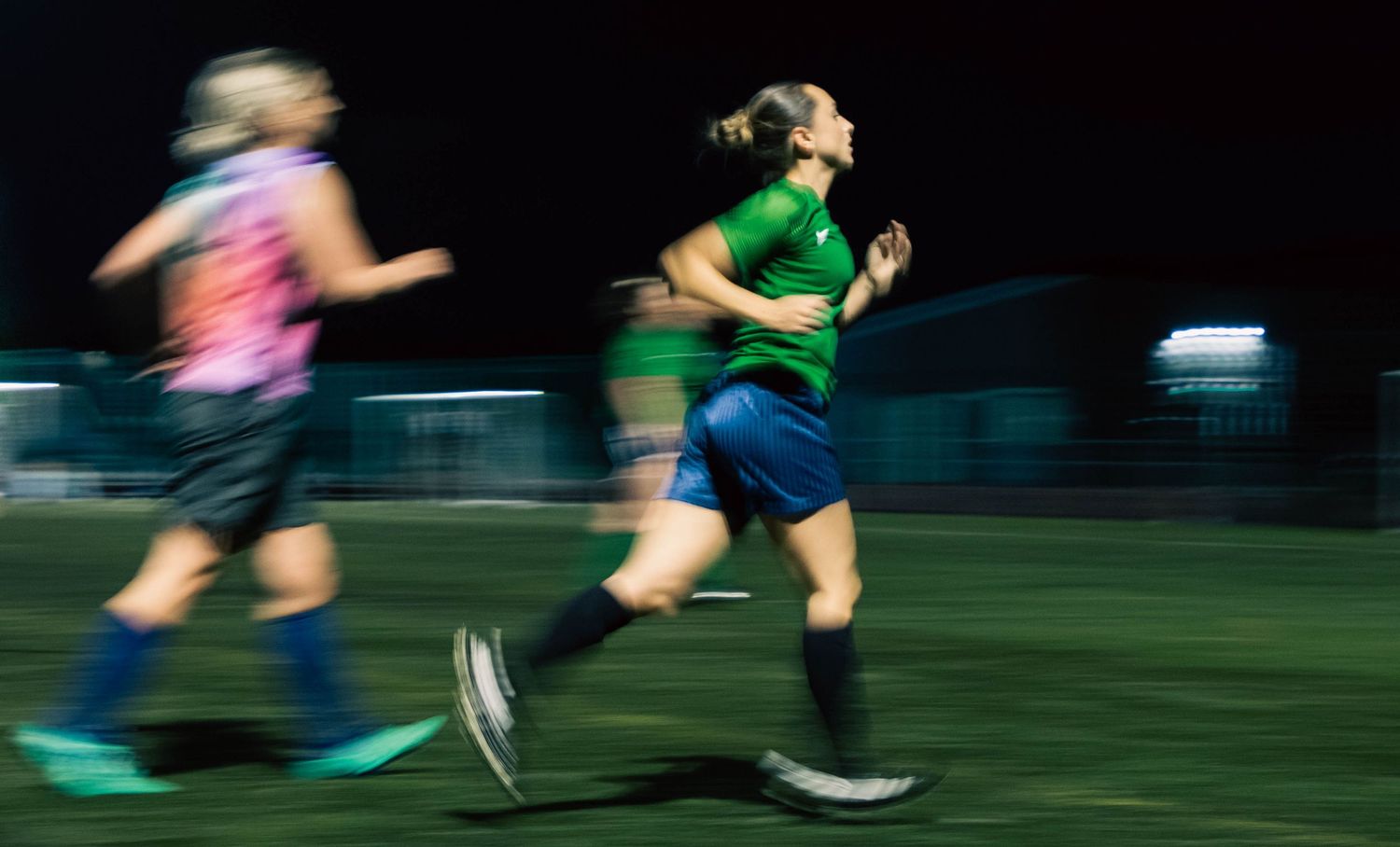 Motion-blurred runners racing across field in athletic competition.