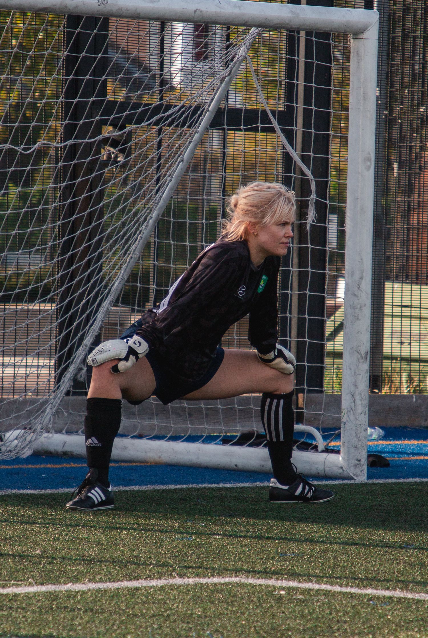 Soccer goalkeeper practicing diving saves in front of goal net.