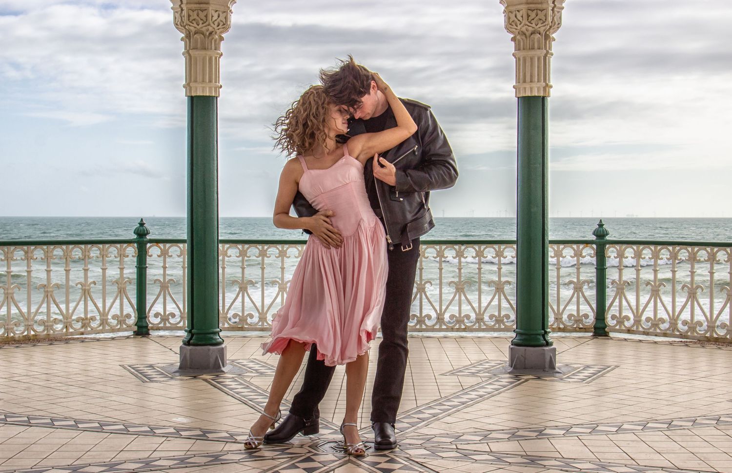 Couple dancing romantically on Victorian seaside pier with ornate columns.