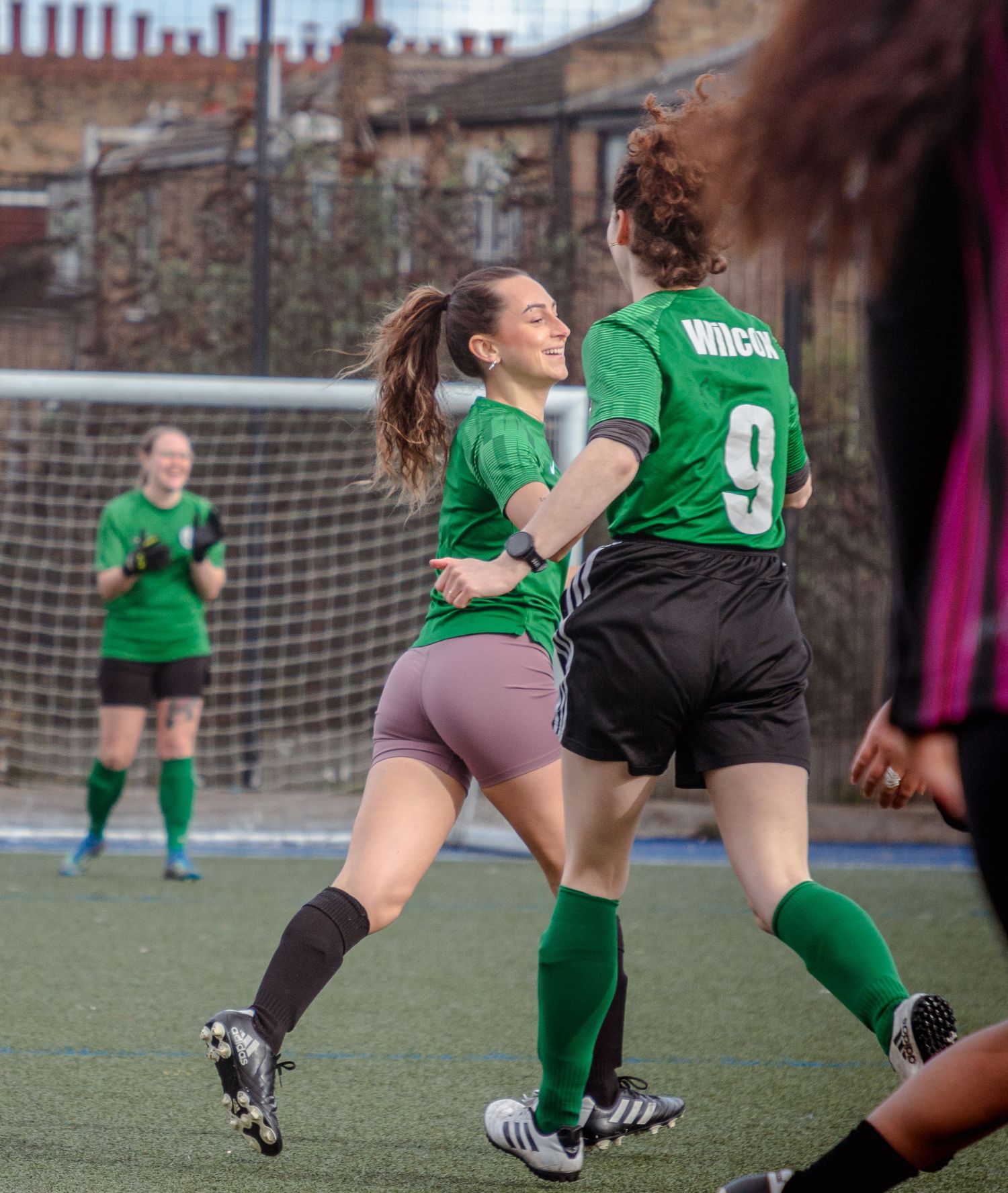 Soccer players in green jerseys compete on an outdoor field during an intense match.
