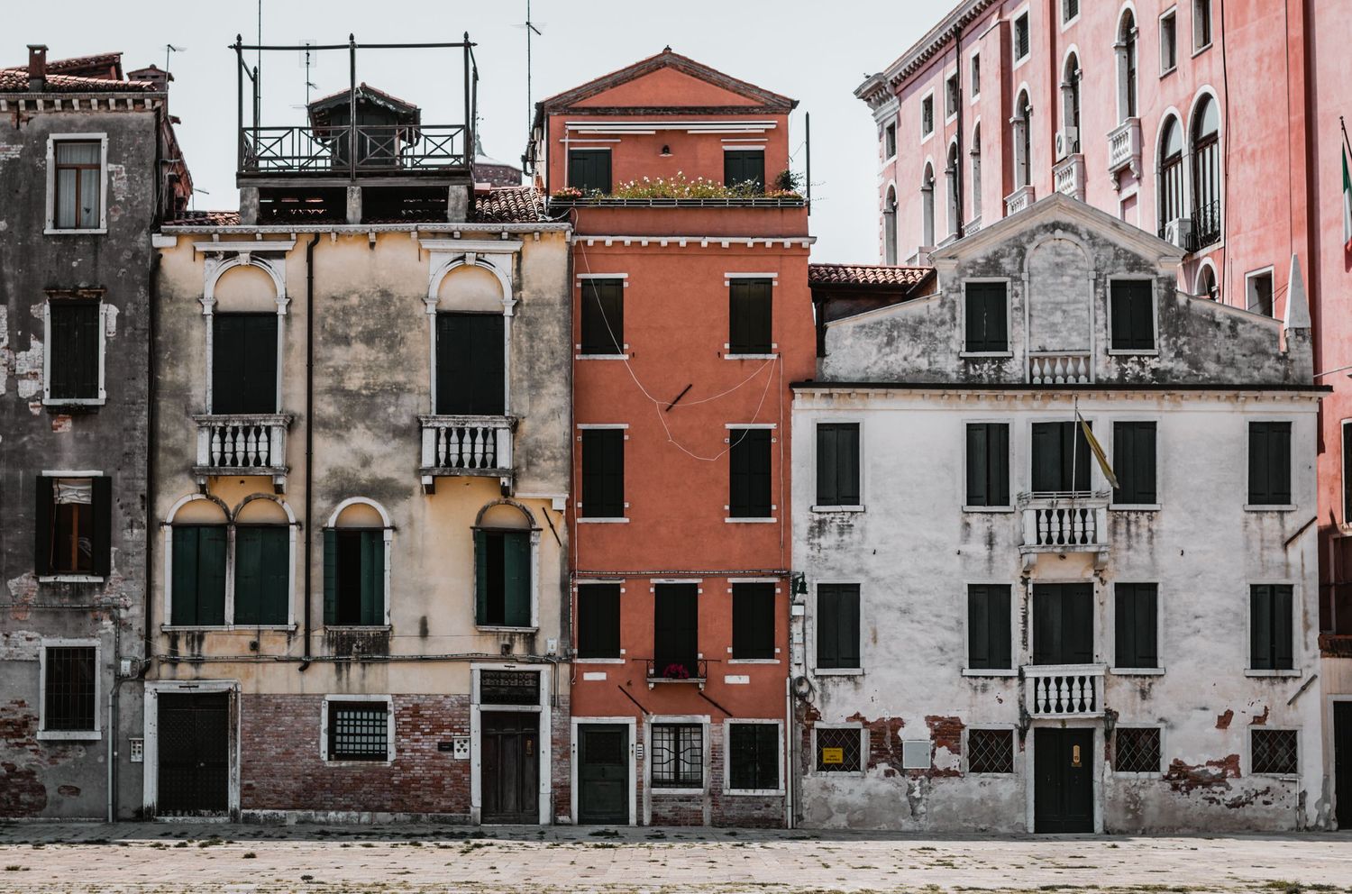 Row of weathered Italian buildings with traditional architecture and terracotta colored facades.