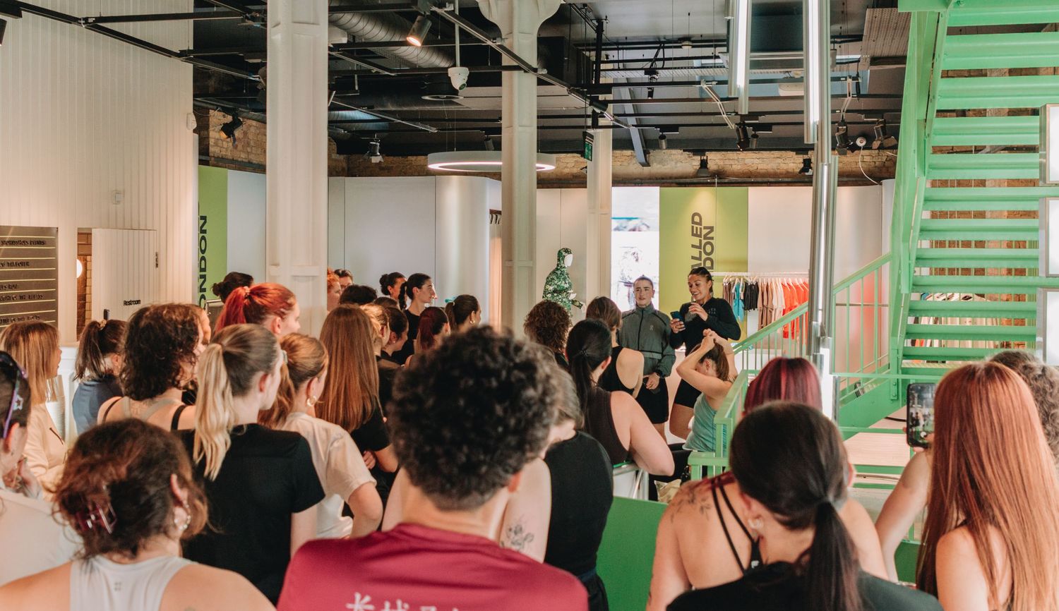 A large group of people attending an indoor event in a modern space with a green staircase.