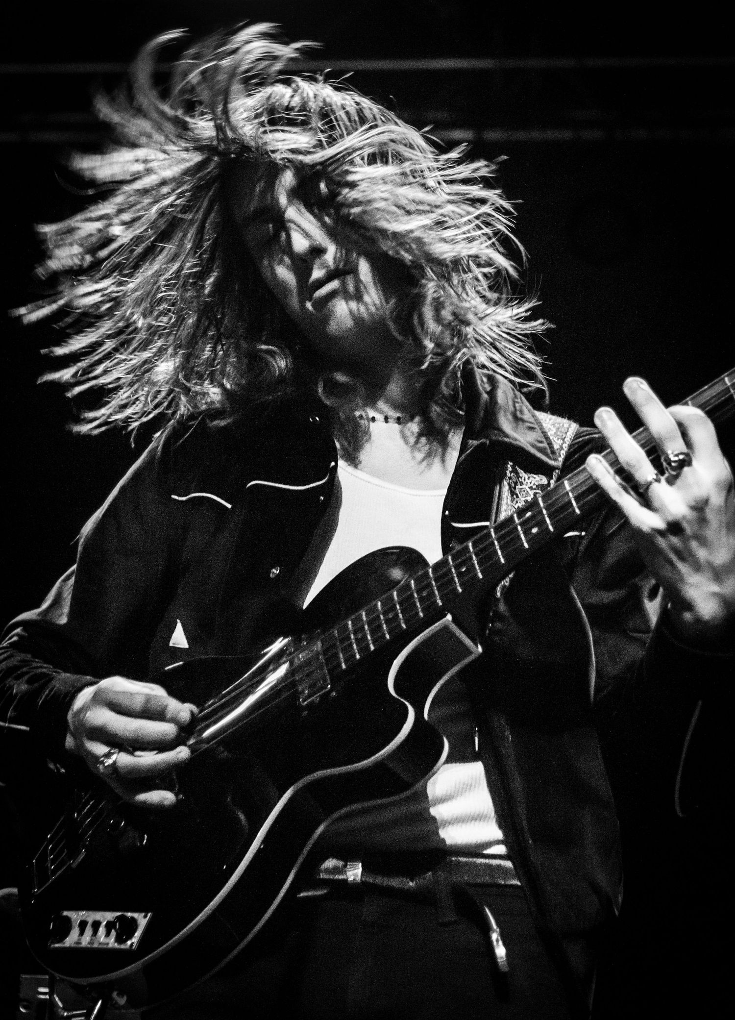 Dramatic black and white photo of guitarist with hair in motion during performance.