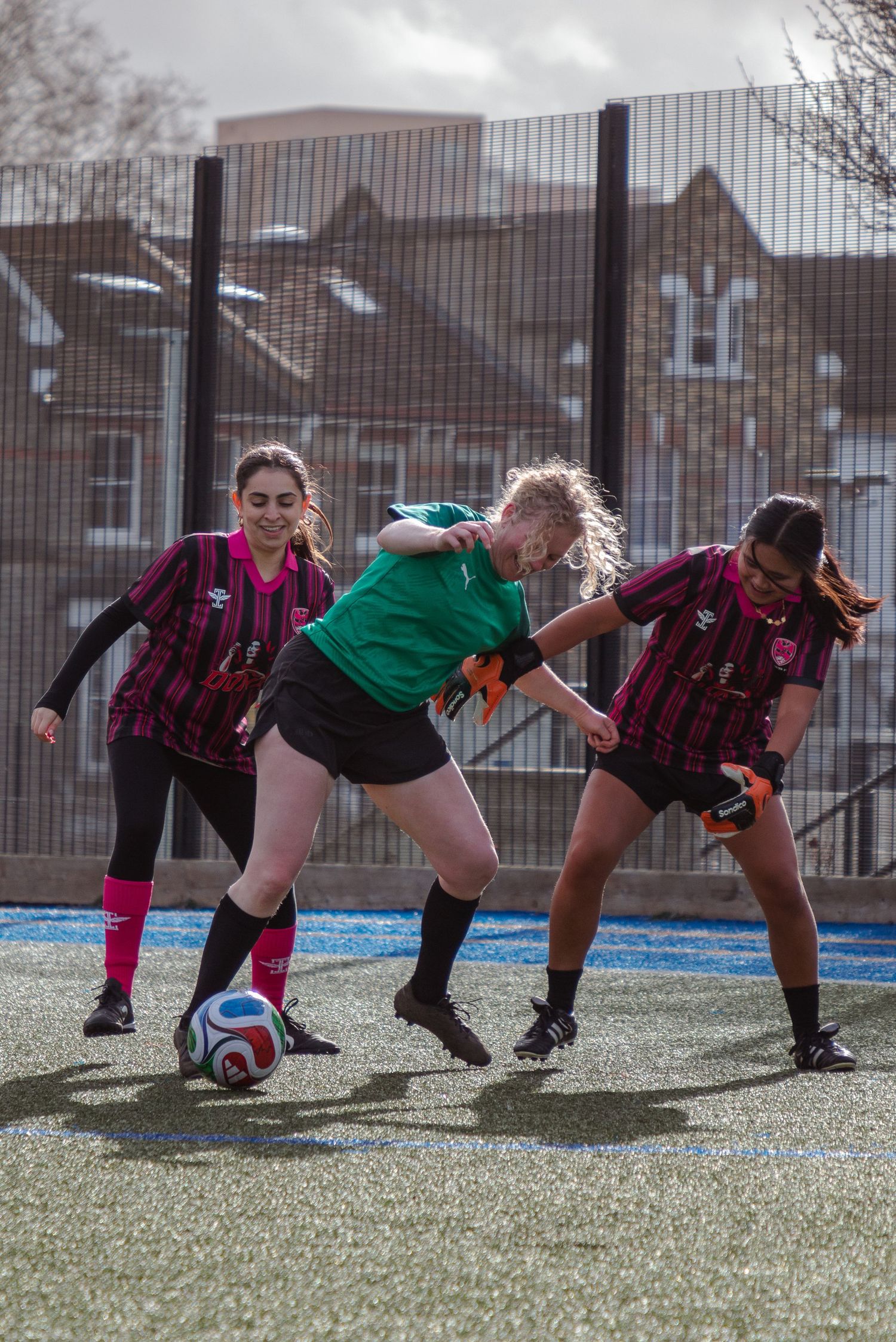 Soccer player in green jersey diving to block a shot during a match on artificial turf field.