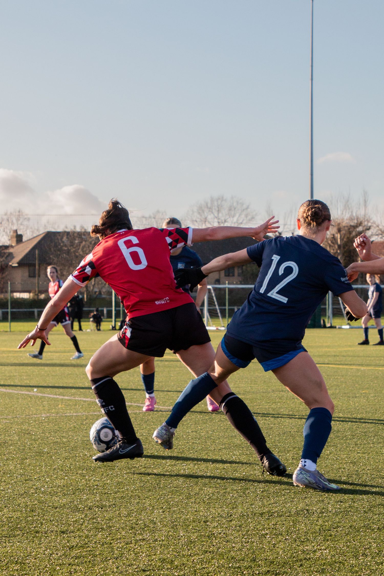 Rugby players from opposing teams compete for possession of the ball during a match on a sunny day.