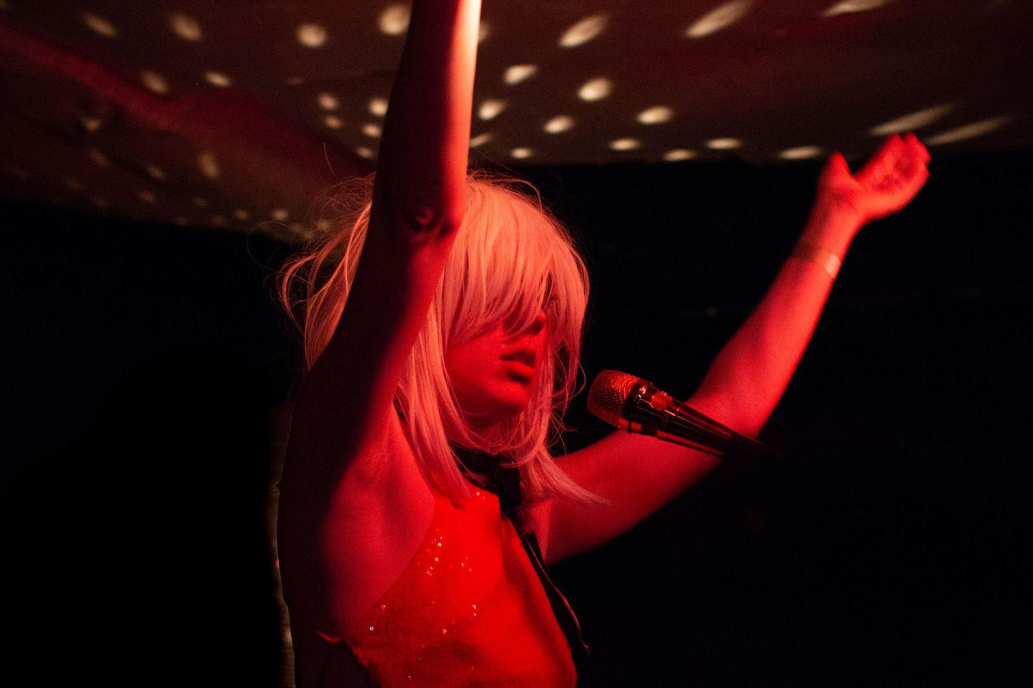 Concert performer illuminated in red stage lighting.