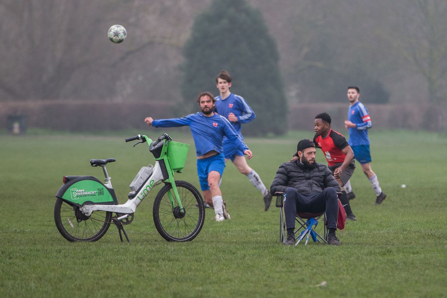 Soccer players rest on the grass field next to their parked bicycles during a break in the game.