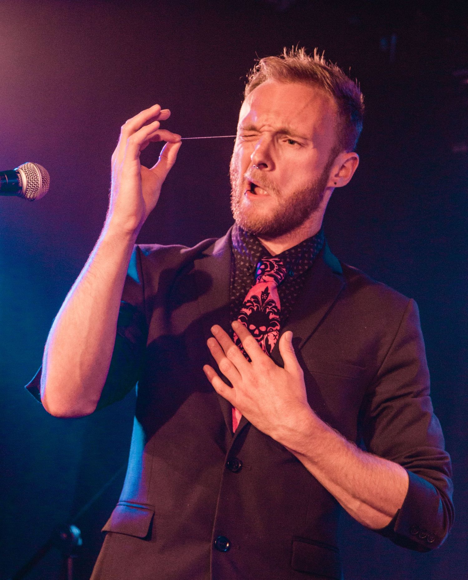 Singer performing emotively on stage with dramatic blue lighting.
