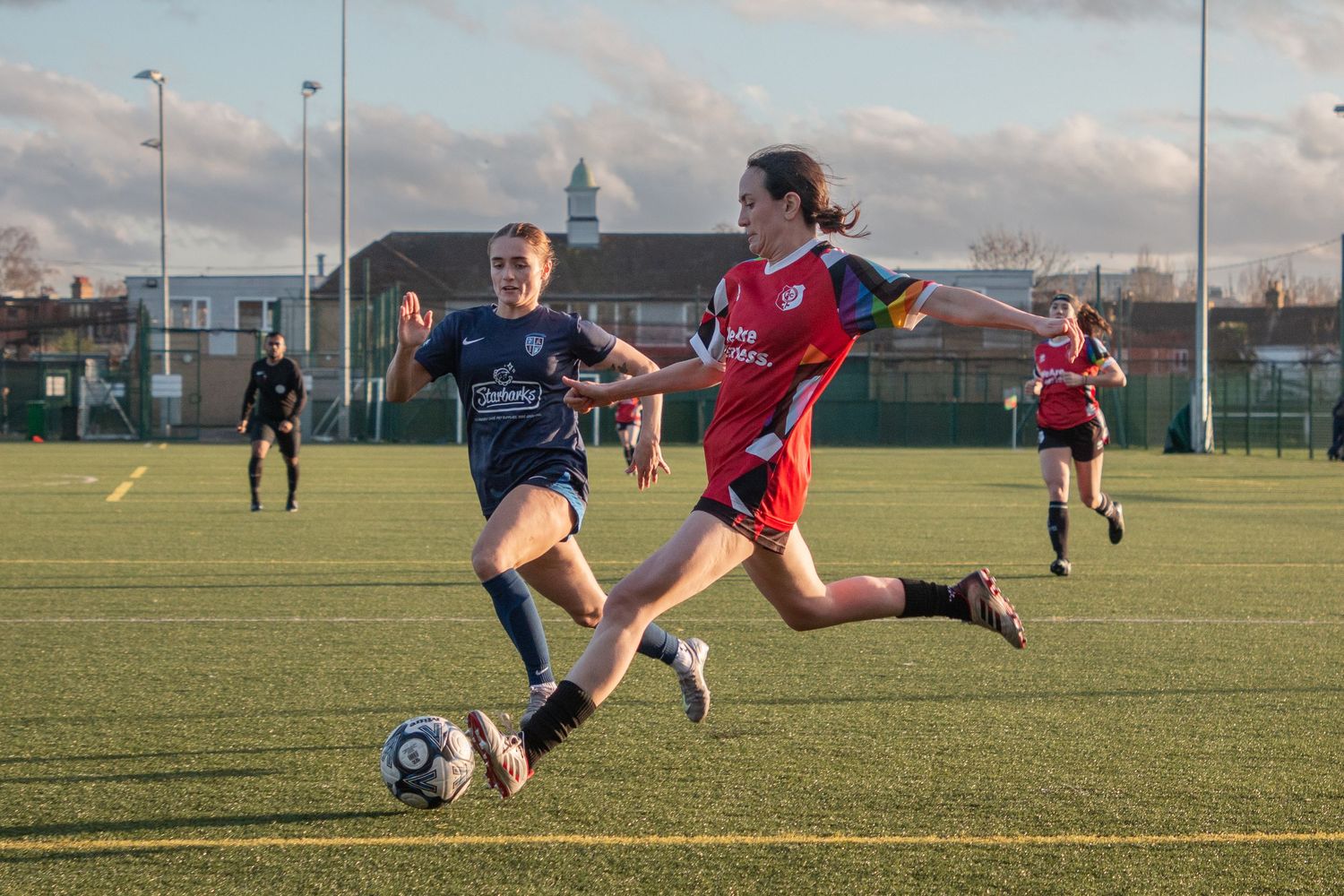 Soccer players compete for possession of the ball on an outdoor turf field during a match.