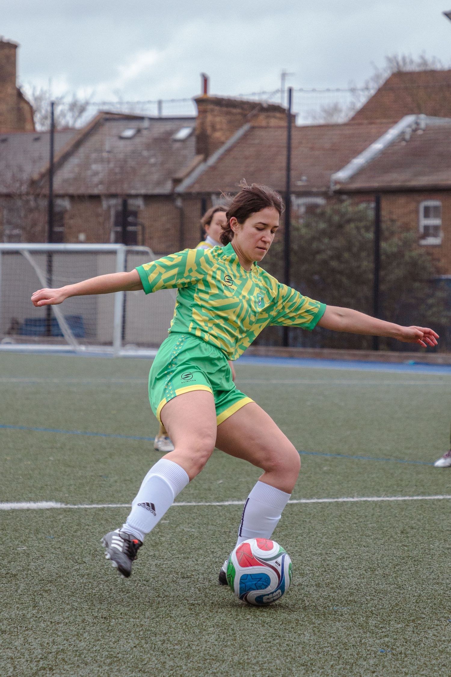 Soccer player in green jersey performs sliding tackle on grass field during match.