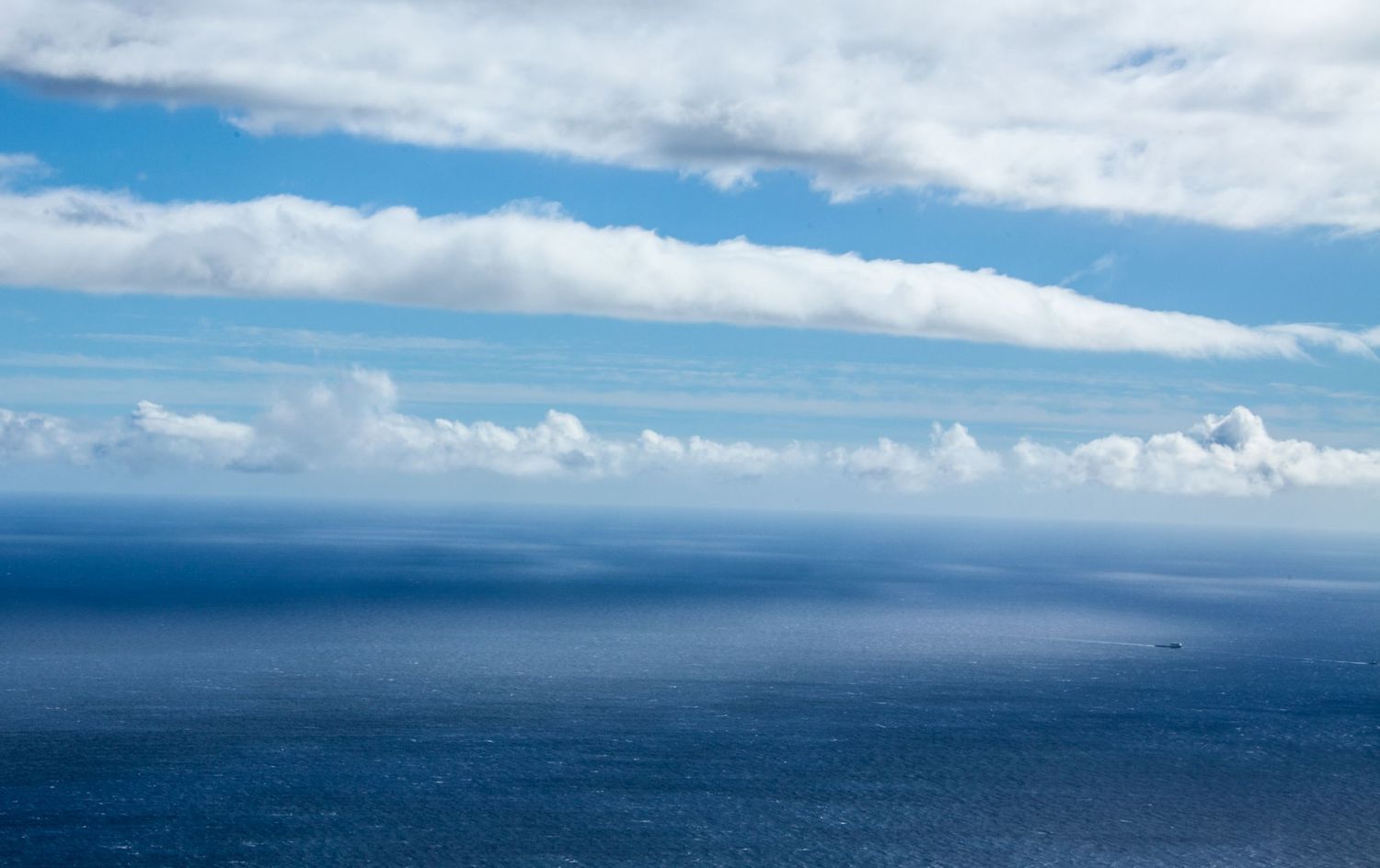 Serene seascape with layers of white clouds over deep blue ocean waters.