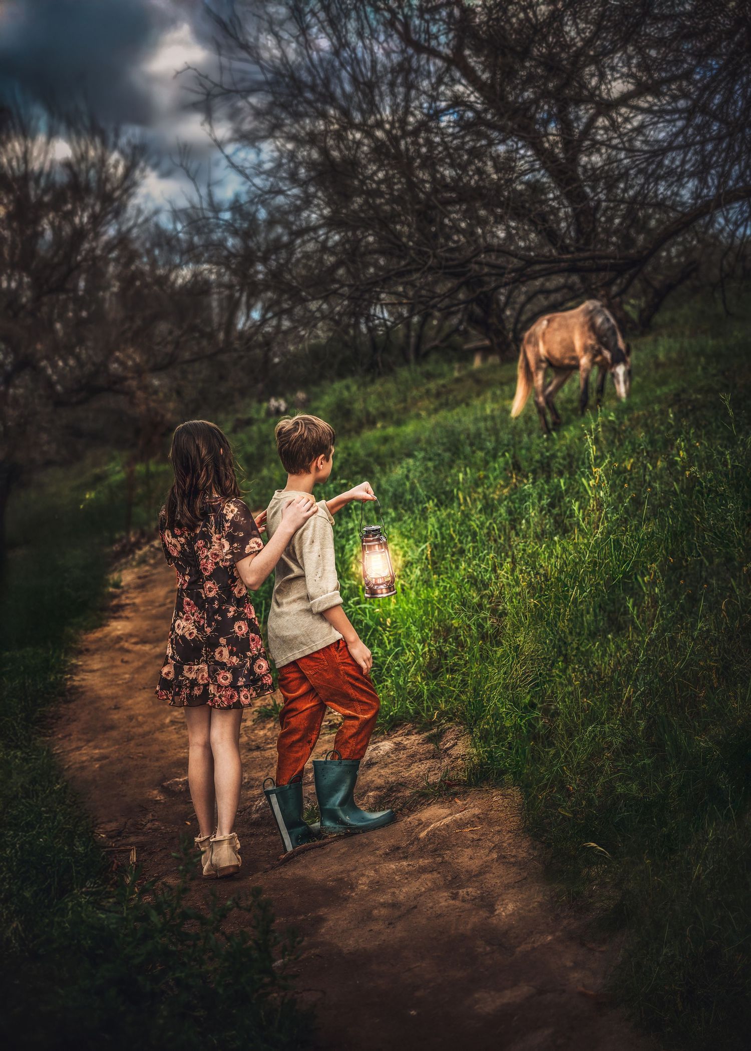Two children walking a lantern-lit path toward a horse grazing in a dark wooded area.