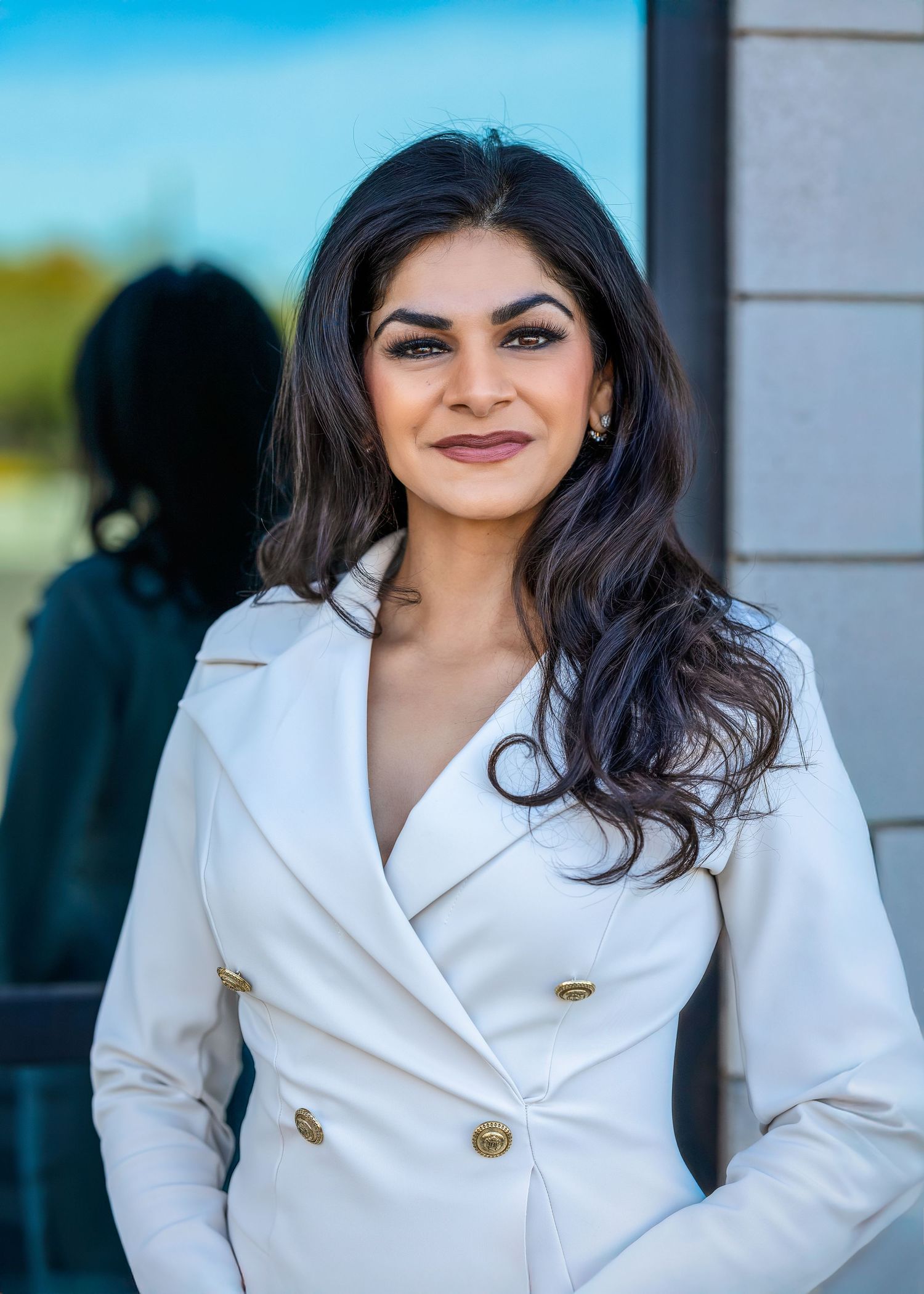 Powerful CEO and female entrepreneur in front of mirrored window wearing a white coat dress.