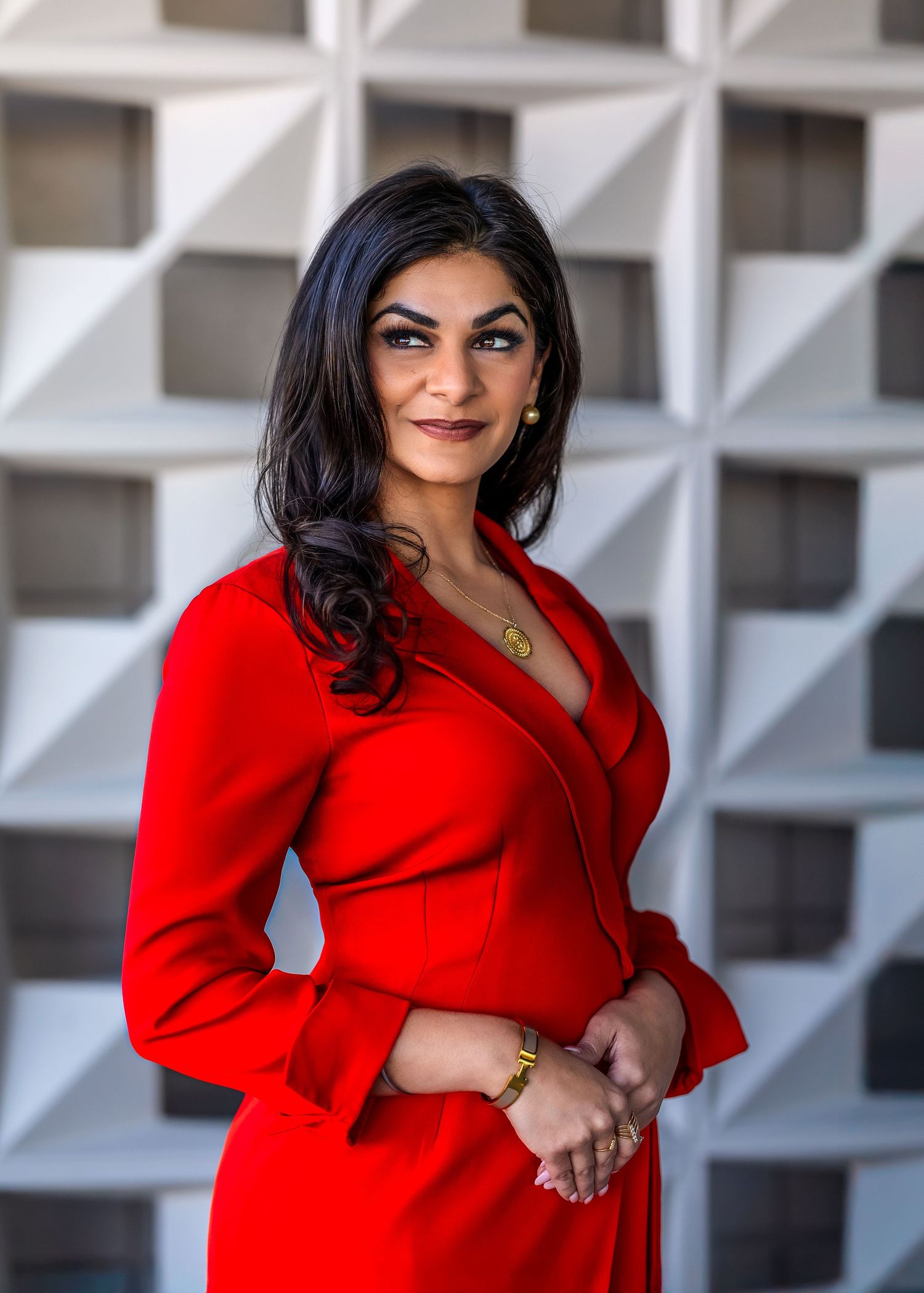 CEO of global brand wearing a red dress and smiling in front of her office building.