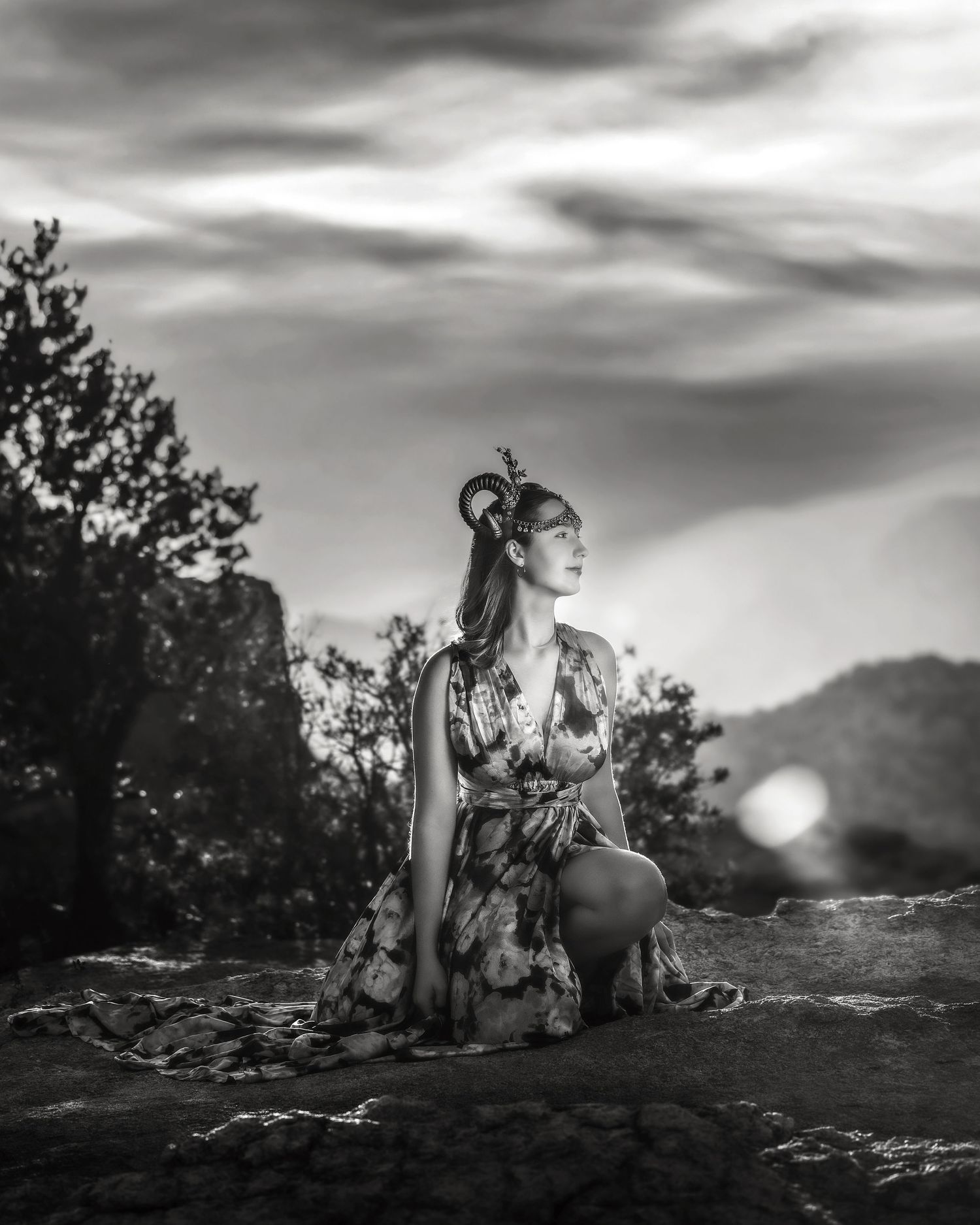 Monochrome portrait of woman in floral dress with antler headpiece gazing upward at dusk.