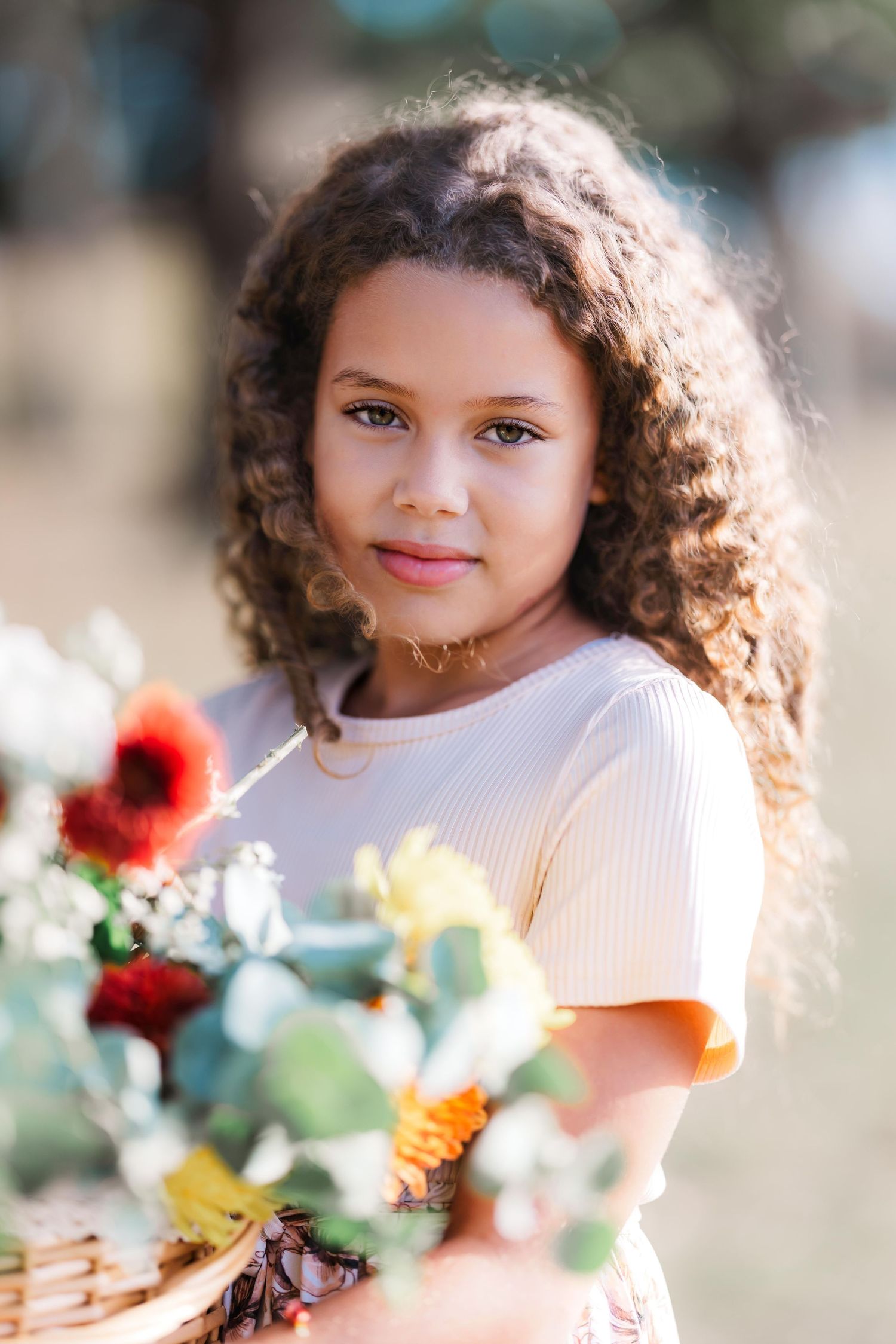 young girl holding a picnic basket full of flowers in golden hour in a field