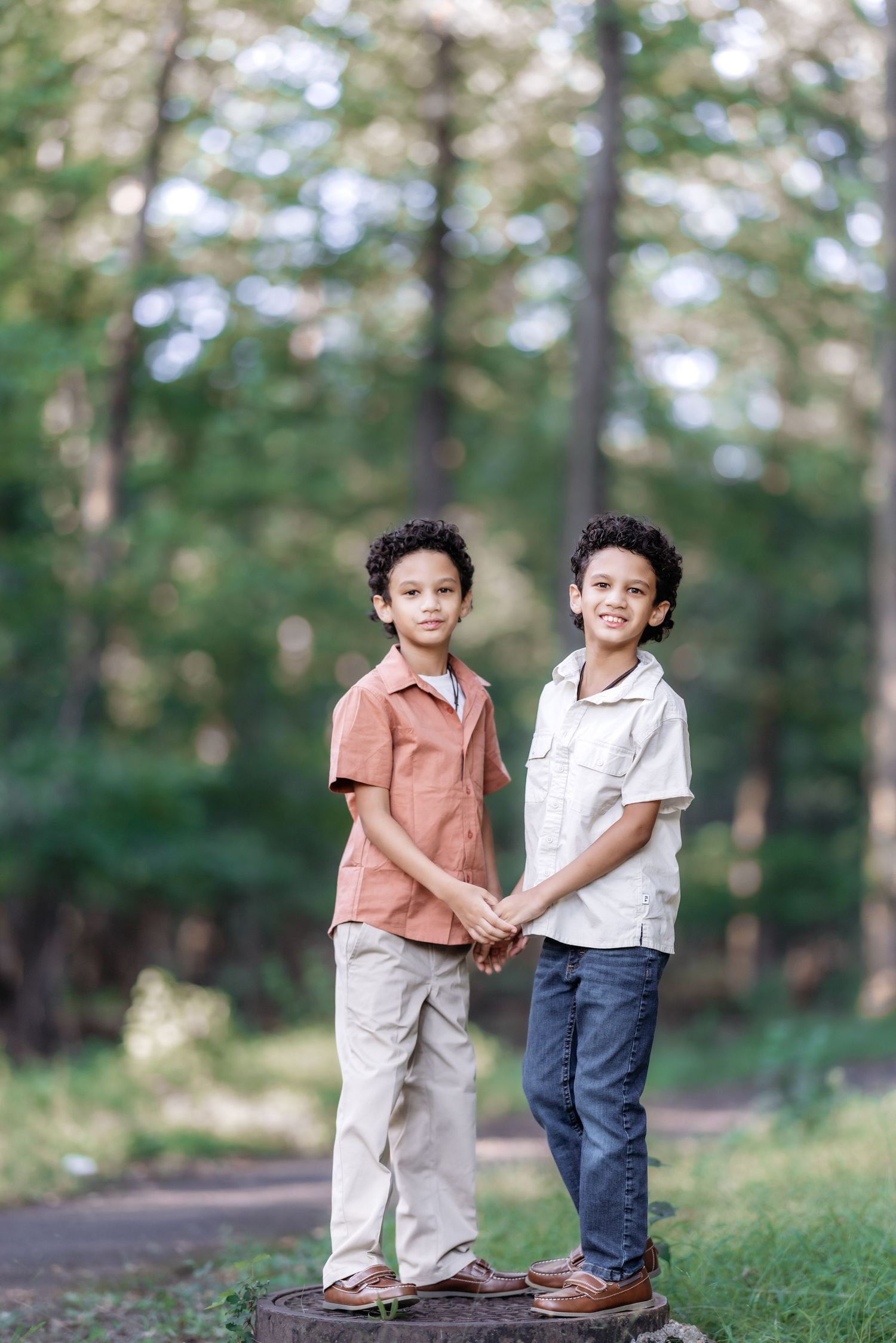 two boys standing on a manhole