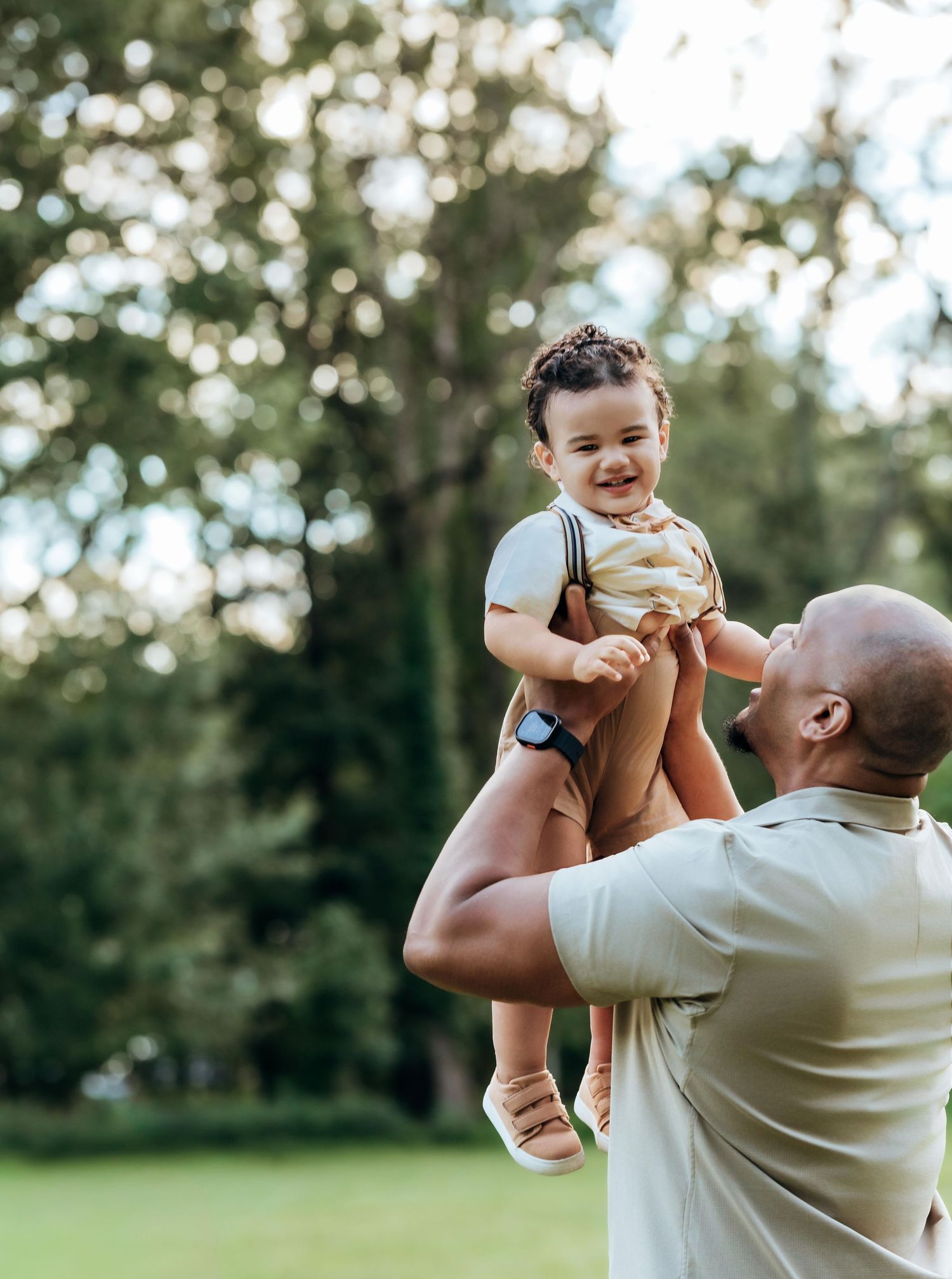 father holds baby high up in the air