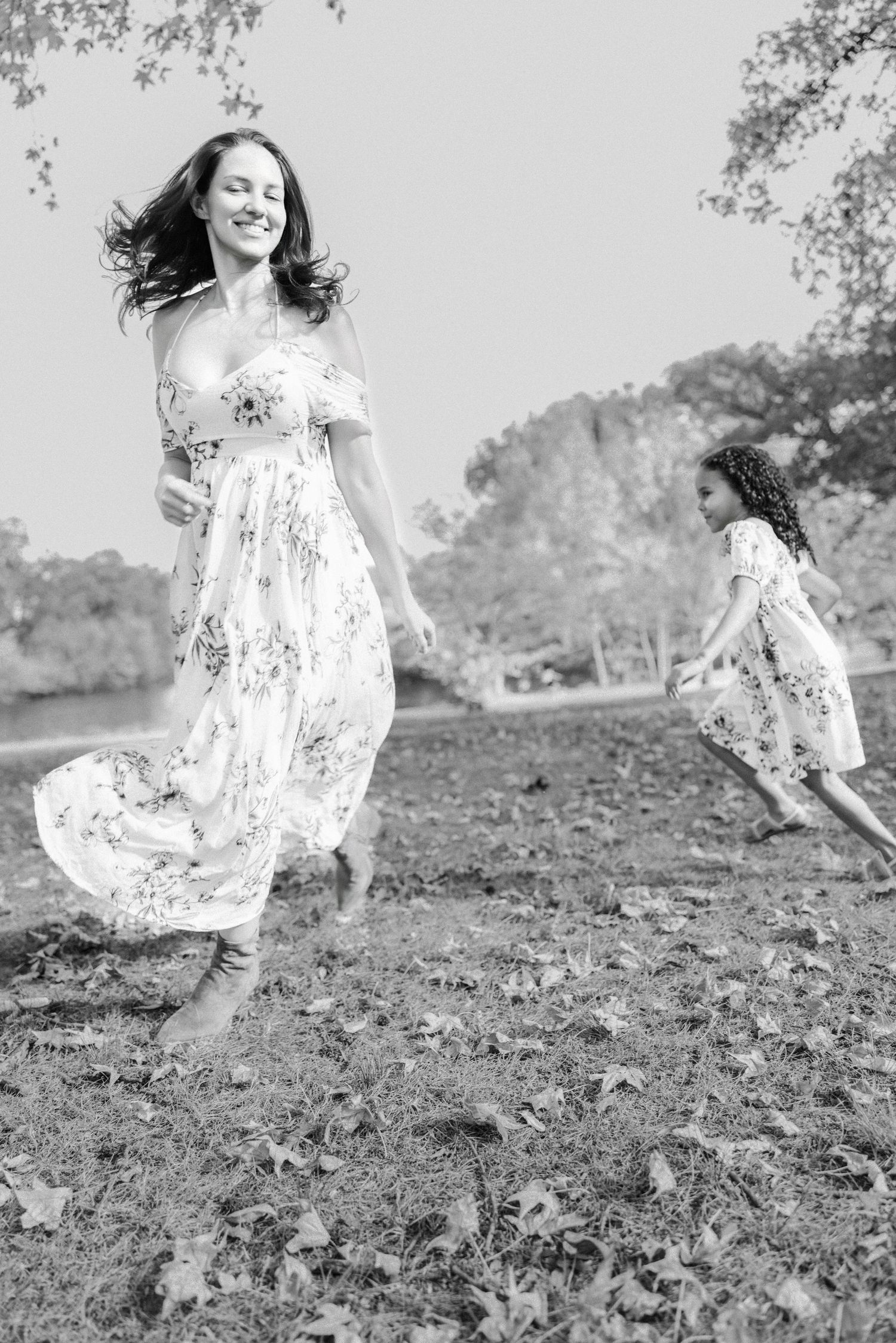 black and white photo of mother chasing daughter while dress flows in the wind