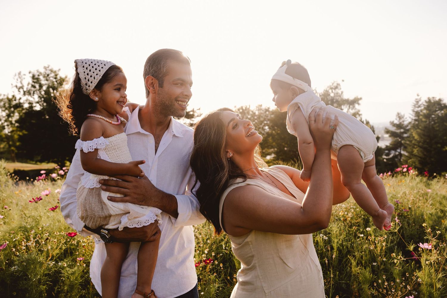 Family enjoying a tender moment together in a sunlit meadow at golden hour.